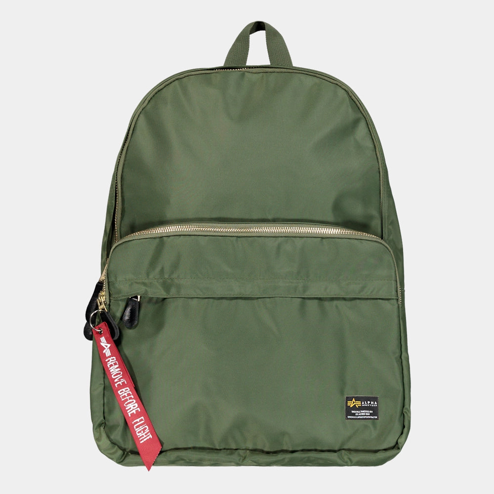 “Grüner (Sage Green) Alpha Industries Crew Backpack aus glänzendem Flight-Nylon mit rotem Remove Before Flight Tag und Utility-Tasche bei Stickabush Berlin.“