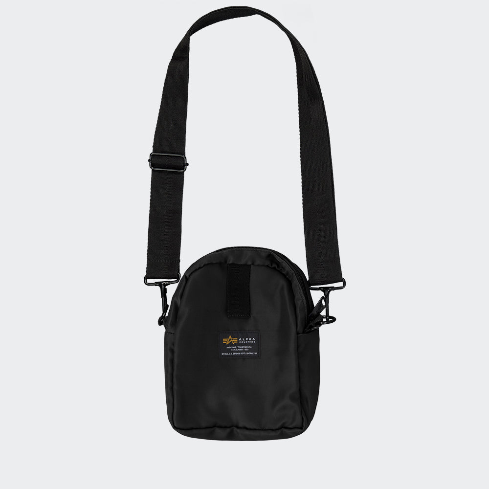 “Alpha Industries Crew Carry Bag – Black. Schwarze Umhaengetasche aus robustem Nylon, mit mehreren Fächern, Tragegriffen und abnehmbarem Schultergurt.“