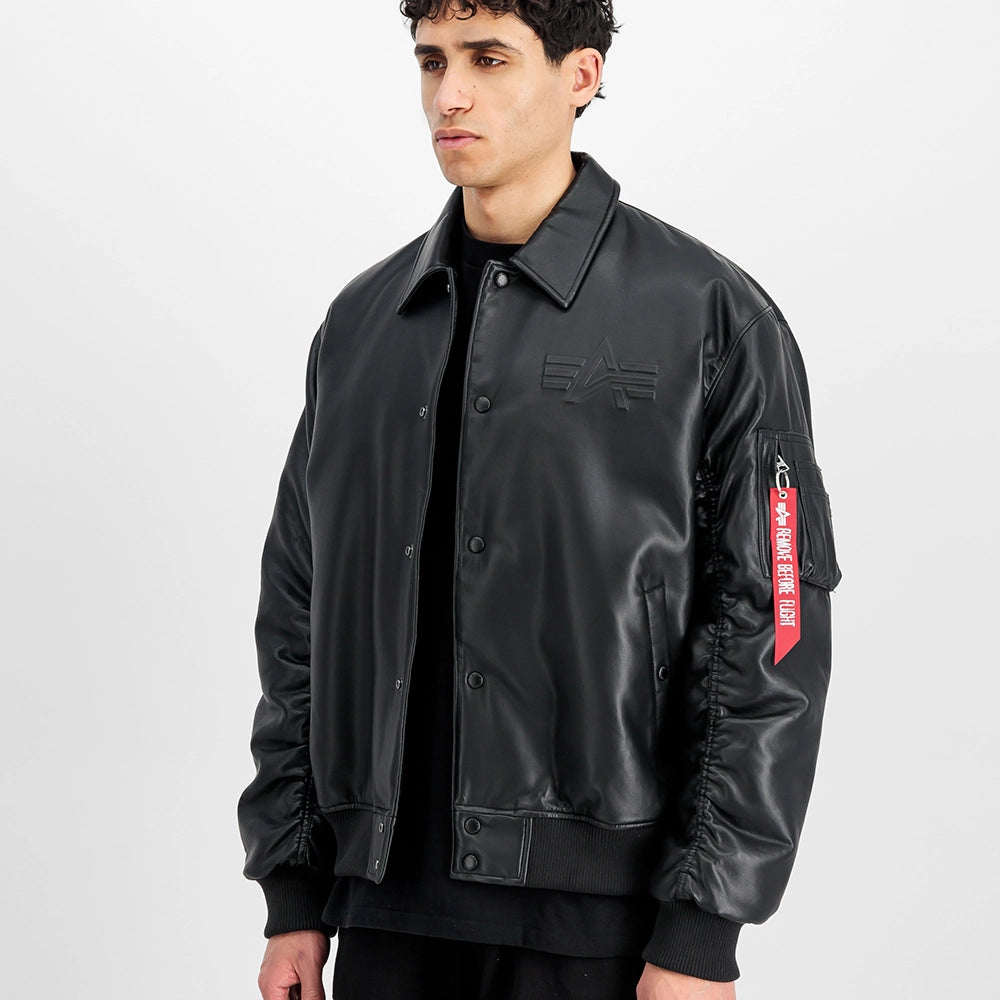 "Schwarze Bomberjacke aus Faux-Leder von Alpha Industries mit gerippten Bündchen, Utility Pocket und Schaumdruck.“
