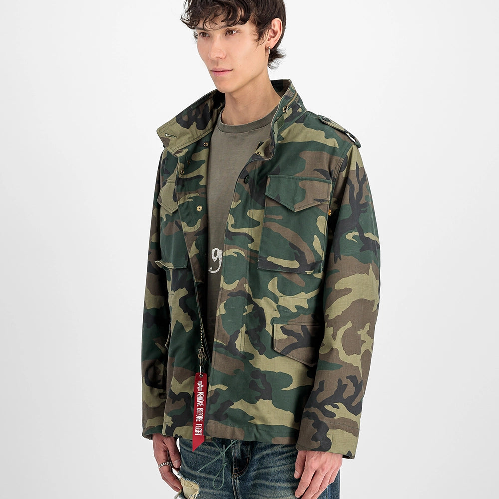 "Camouflage-Feldjacke aus Baumwoll-Mischung von Alpha Industries. Mit vier Pattentaschen, verdeckter Kapuze und Logo-Print auf dem Rücken.“