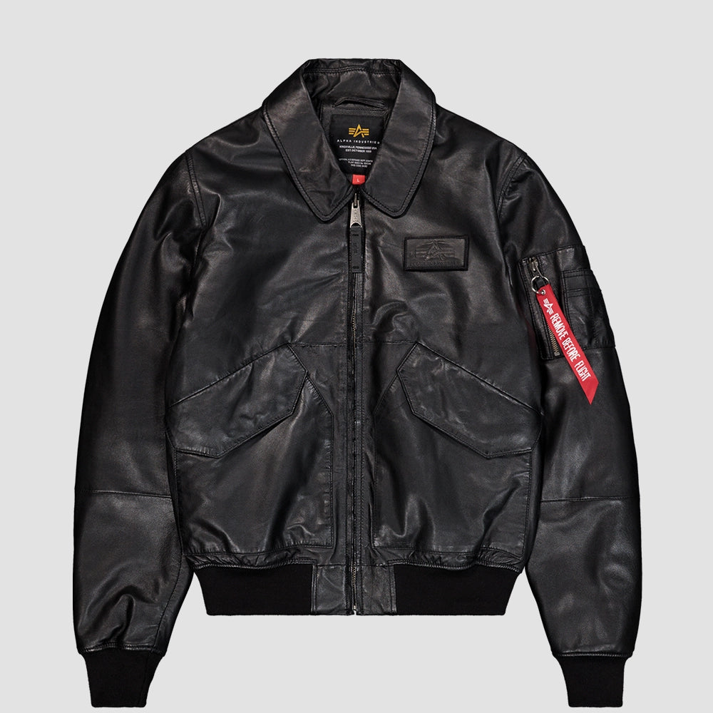 „Schwarze Alpha Industries CWU-45/P Bomberjacke aus hochwertigem Leder mit Umlegekragen, großen Klappentaschen und rotem Remove Before Flight Anhänger bei Stickabush Berlin.“