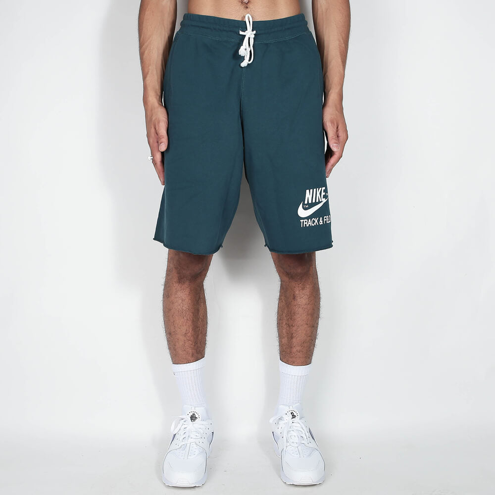 „Nike Sportswear Club Alumni Shorts für Herren mit ungesäumten Kanten, elastischem Bund und Nike Track & Field Logo-Print auf dem Oberschenkel bei Stickabush Berlin.“