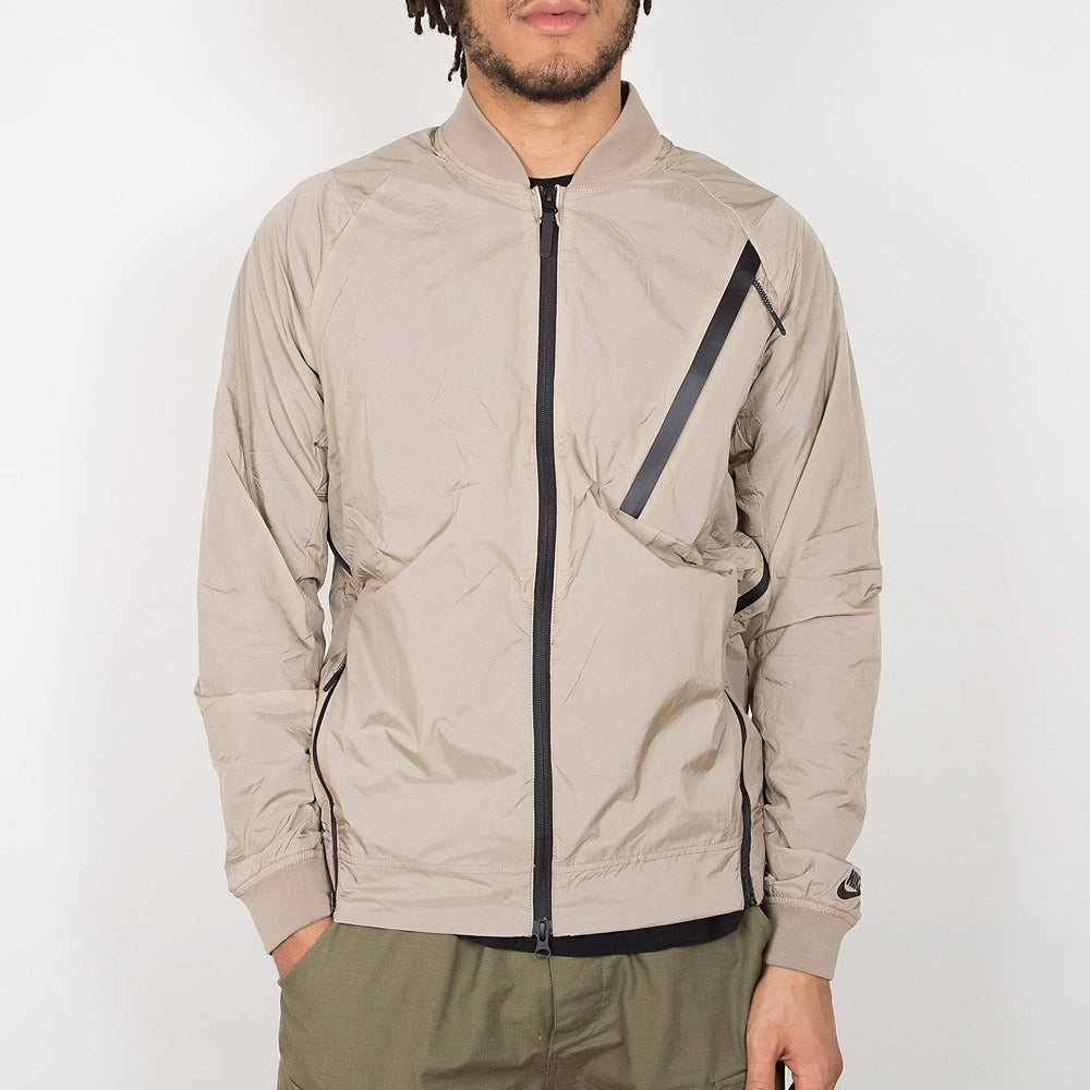“Nike Tech Hypermesh Varsity Jacket in Khaki. Jacke aus gewebtem Material und atmungsaktivem Mesh, mit schwarzen und weißen Akzenten.“