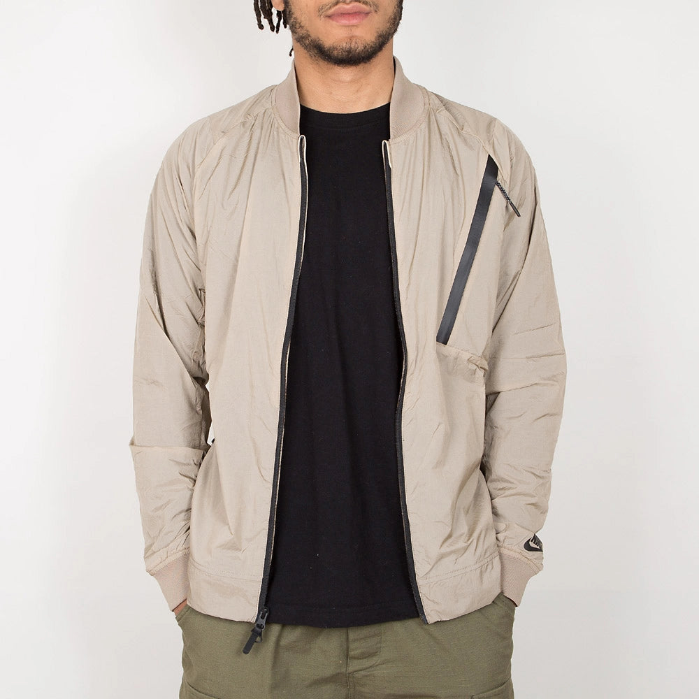 “Nike Tech Hypermesh Varsity Jacket in Khaki. Jacke aus gewebtem Material und atmungsaktivem Mesh, mit schwarzen und weißen Akzenten.“
