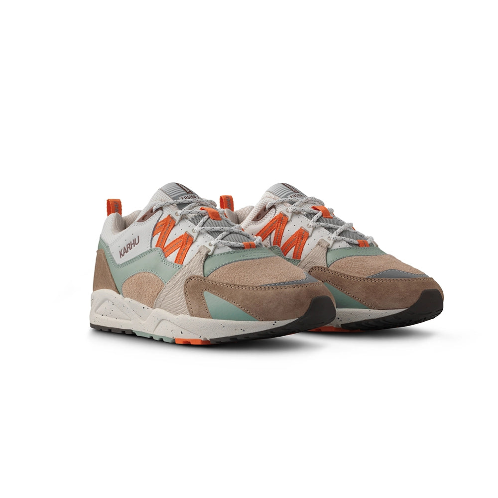 "Wildleder-Sneaker in warmen Braun- und Orangetönen mit beigem Mesh und dem Karhu 'M'-Logo.“