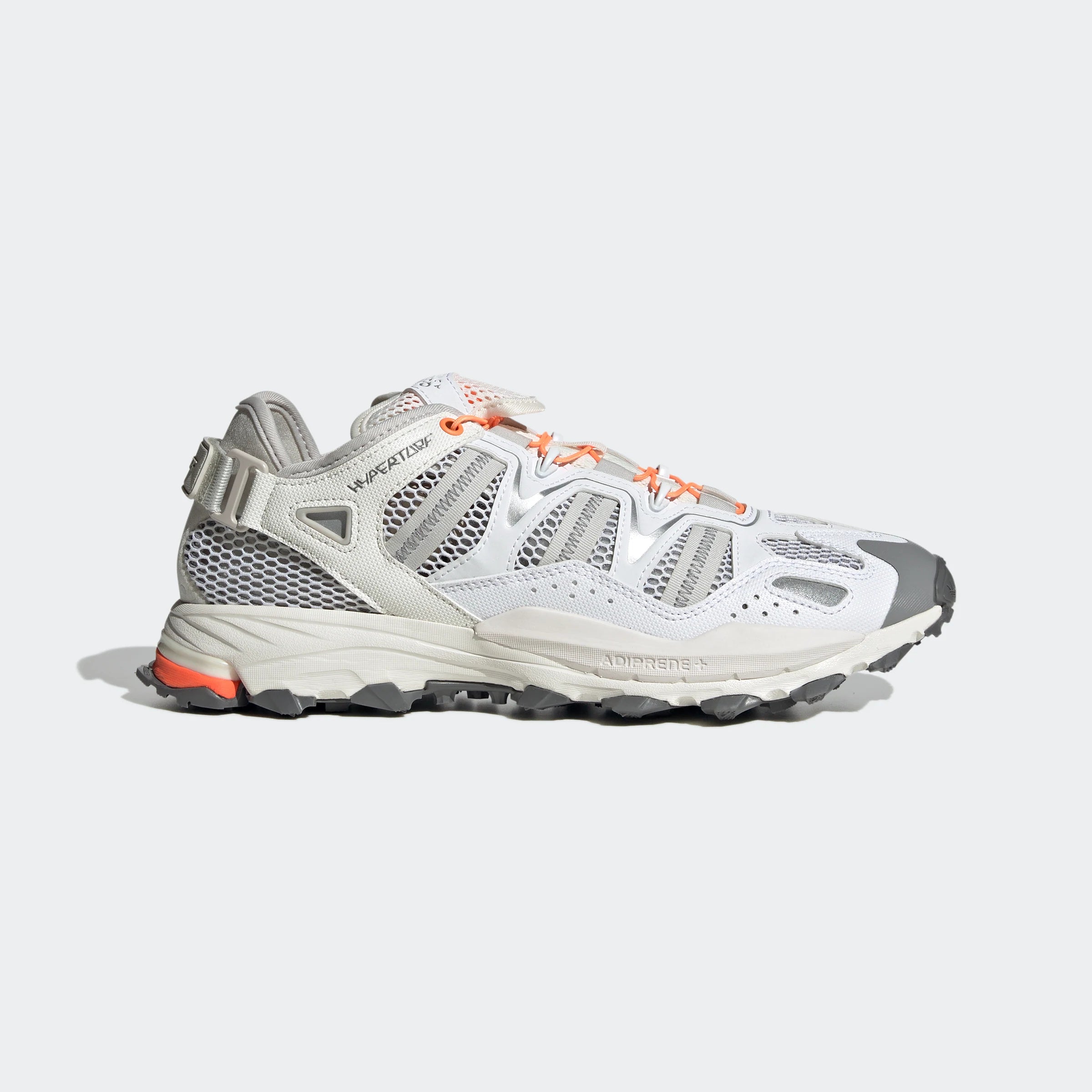 “Weiße ("Footwear White") Adidas Hyperturf Sneaker mit grauen und orangefarbenen Akzenten. Trail-inspirierte Schuhe aus Textil und Synthetik-Wildleder, mit Adiprene+-Dämpfung und markanter Außensohle.“