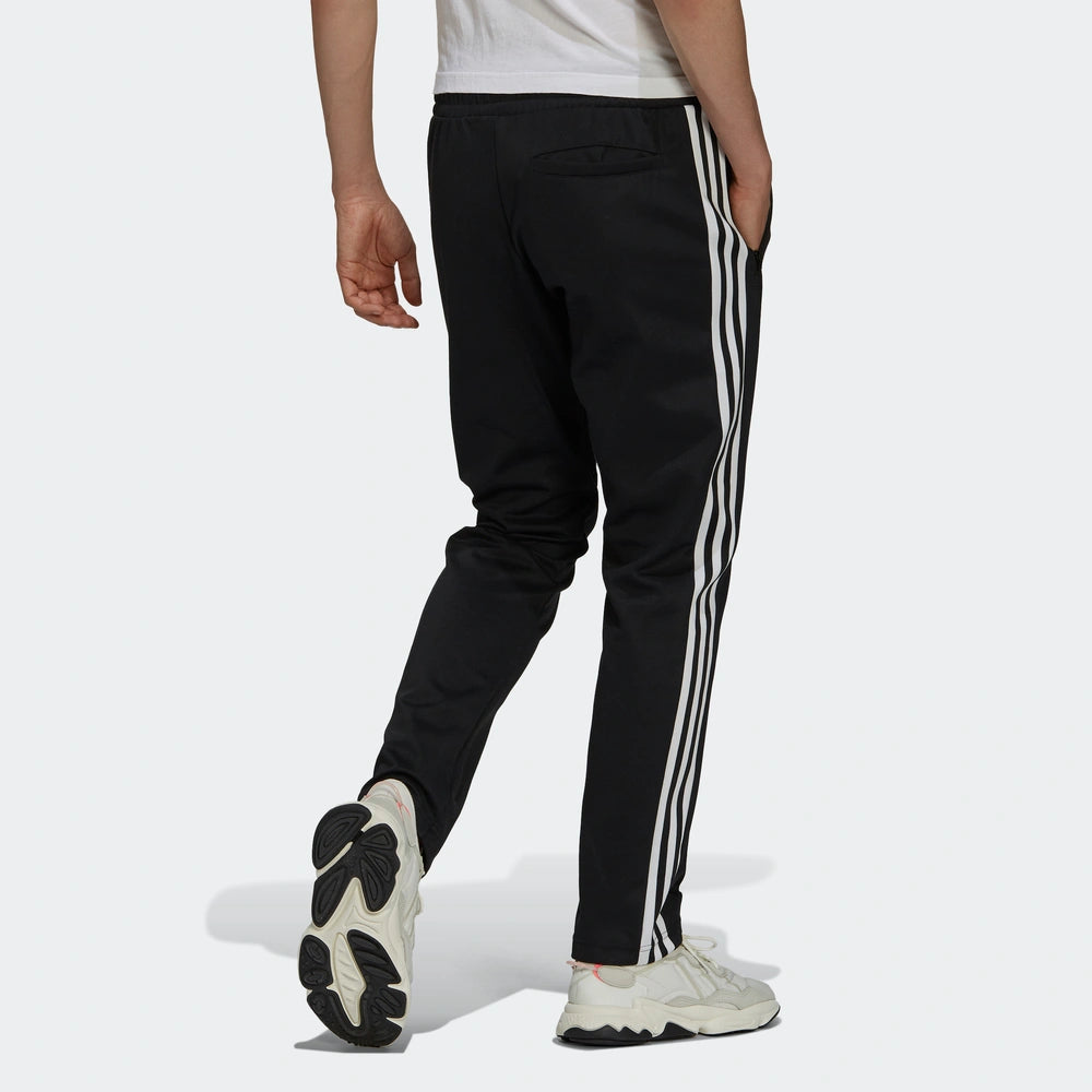 "Adidas Classics Beckenbauer Track Pants, Black, glattes Trikotmaterial (vermutlich Polyester), klassische Trainingshose mit drei weißen Streifen und Reißverschlusstaschen."