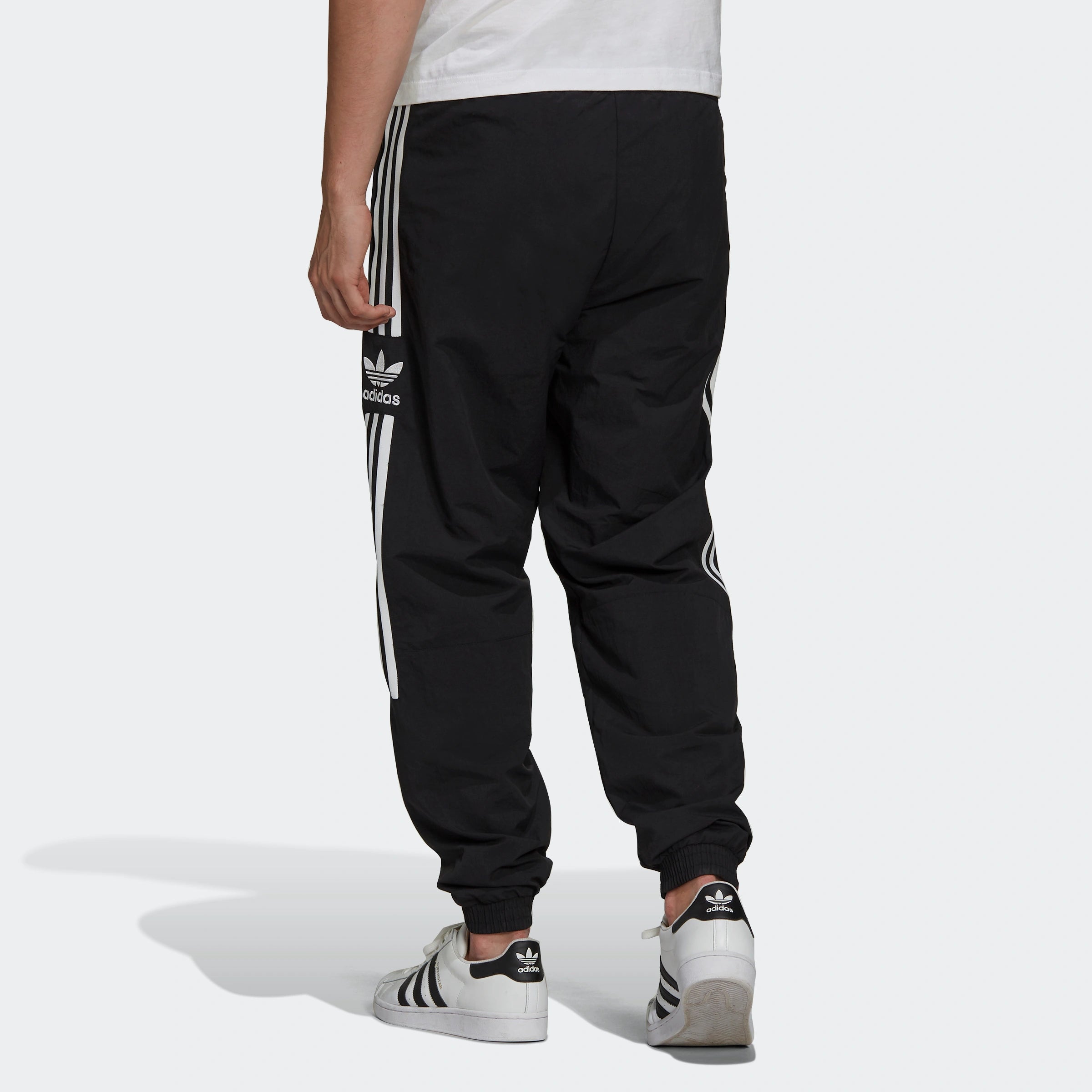 "Schwarze Adidas Trainingshose mit weißen seitlichen Streifen und weißem Trefoil-Logo am Bein. Klassischer Schnitt mit elastischem Bund und Bündchen."