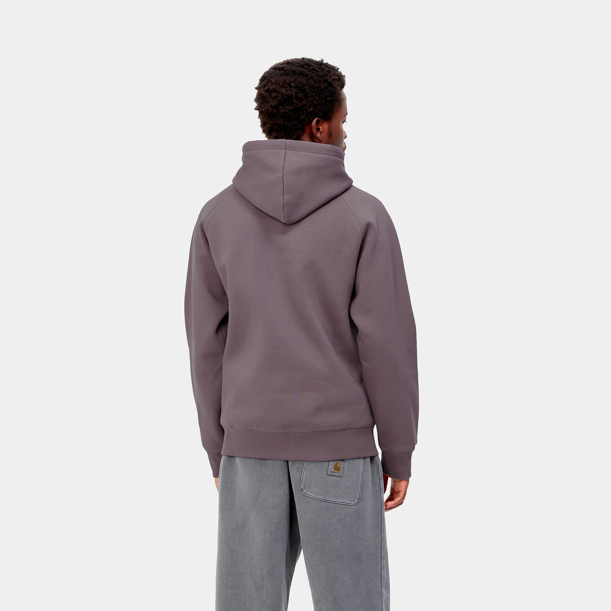 "Carhartt WIP Hooded Chase Sweat – Misty Thistle. Lila Hoodie aus Baumwoll-Polyester-Mix, mit Kapuze, Kängurutasche und gesticktem, goldenem Carhartt WIP Logo am Ärmel." 