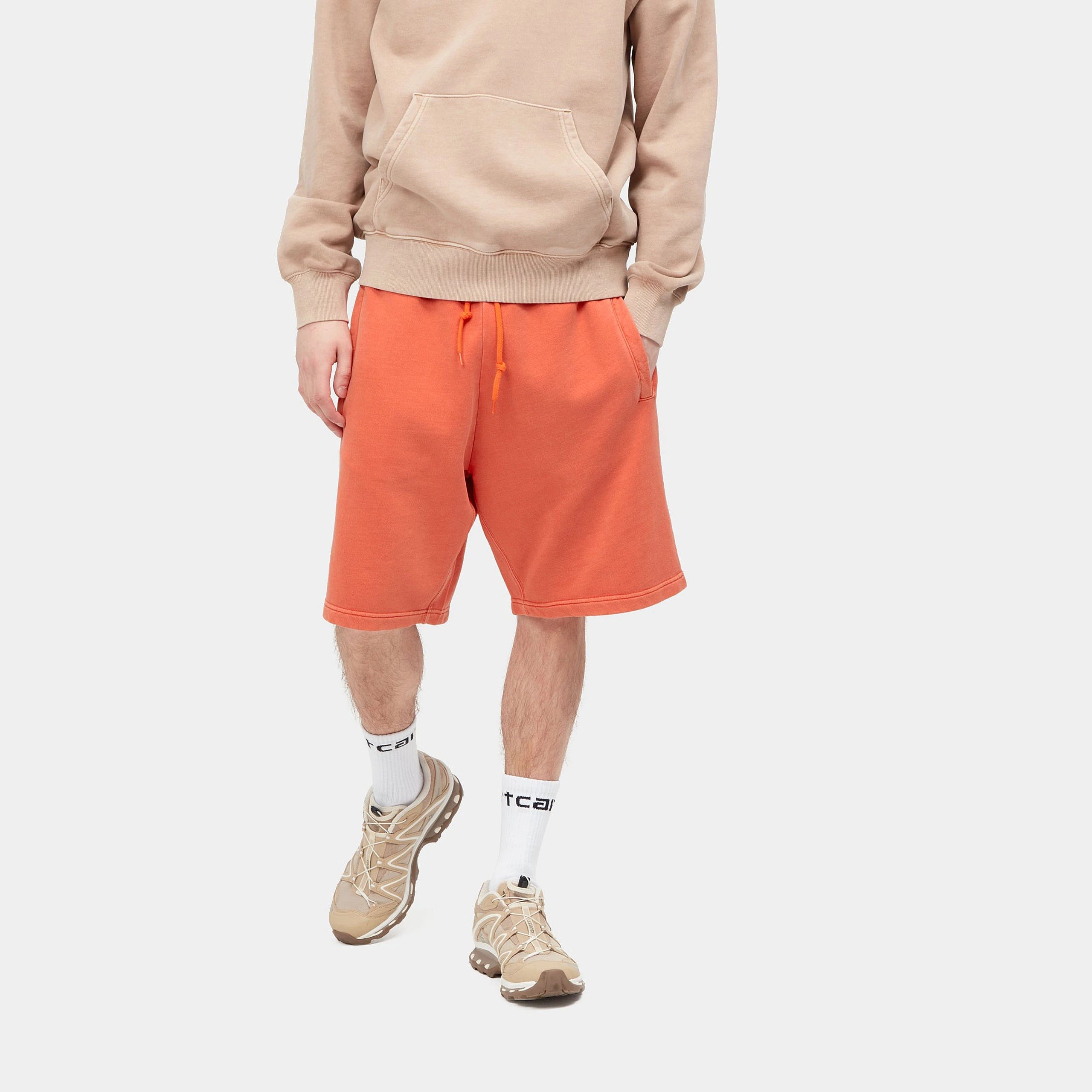“Helles Orange ("Elba") Carhartt WIP Nelson Sweat Shorts. Kurze Herren-Sweathose aus weichem, stückgefärbtem Baumwolljersey. Lockere Passform, elastischer Bund mit Kordelzug, zwei Seitentaschen und eine Gesäßtasche mit kleinem, gewebtem Logo-Etikett. Bequeme Freizeithose für warme Tage.“