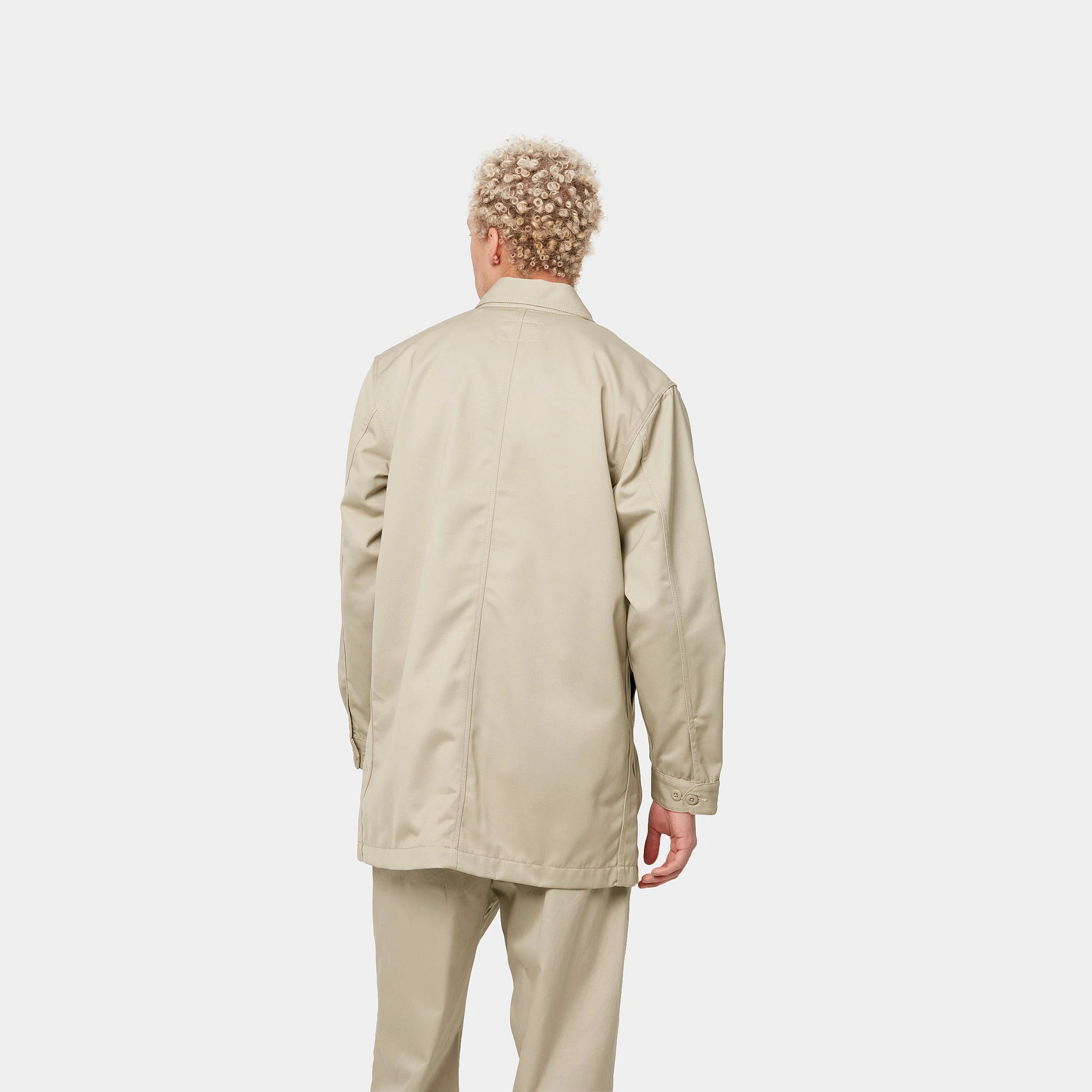 "Carhartt WIP Modular Coat – Wall. Beiger Mantel aus robustem Baumwoll-Twill, mit verdeckte Knopfleiste vorne und aufgesetzten Taschen."