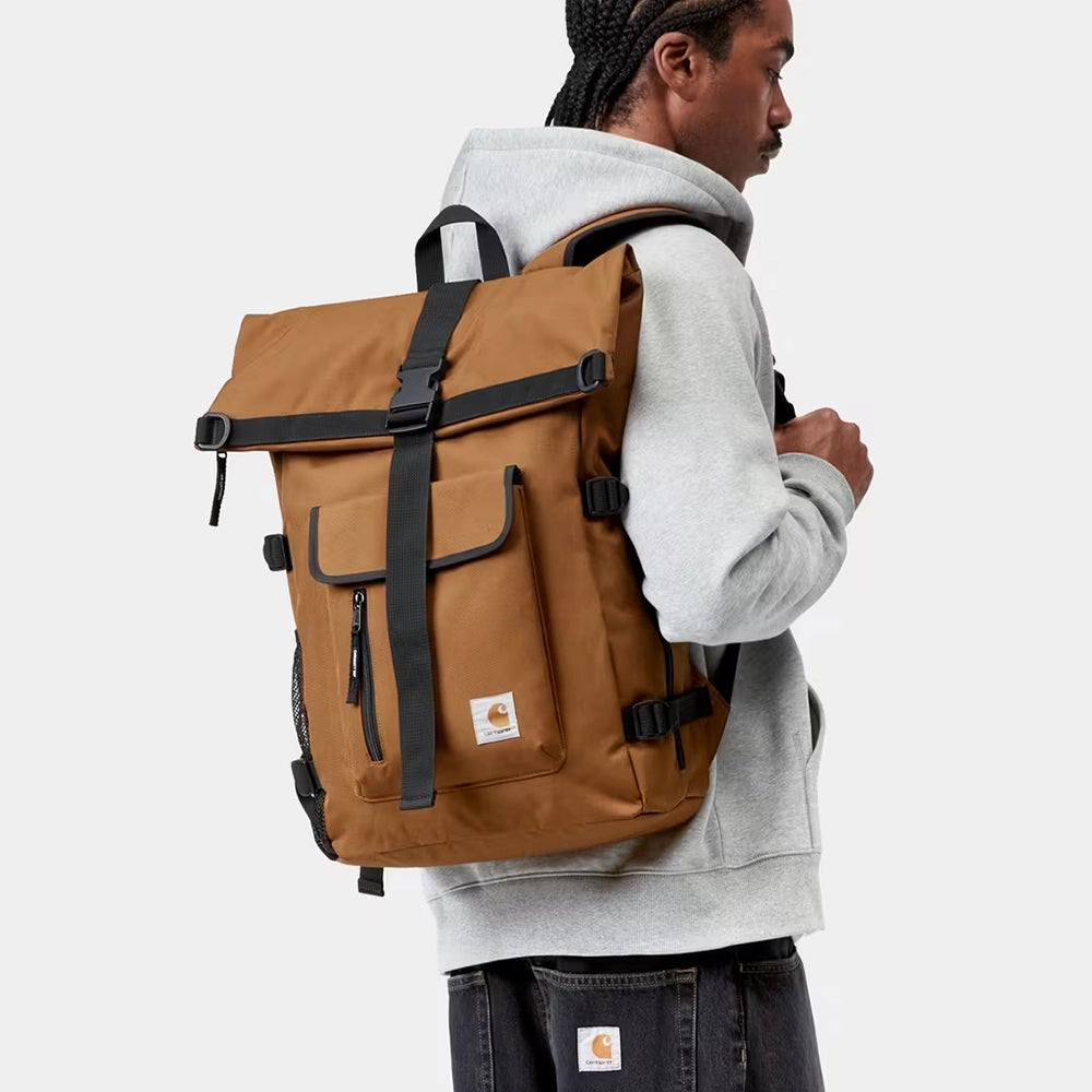 “Carhartt WIP Philis Backpack in Hamilton Brown mit Roll-Top Verschluss und quadratischem Carhartt Logo-Label bei Stickabush Berlin.“