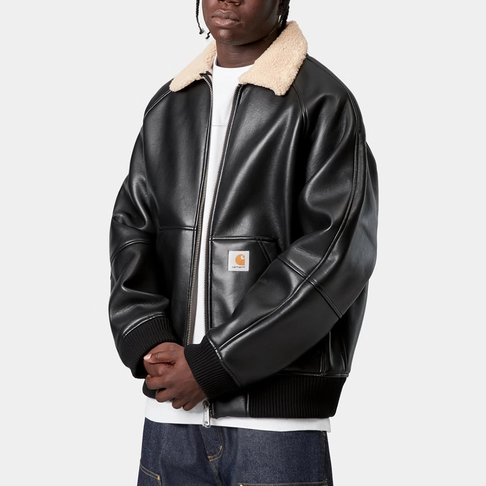 „Carhartt WIP Shepton Jacket in Schwarz/Natur, aus Kunstleder und warmem Fleece, mit Kontrastärmeln, Frontzipper und praktischen Taschen.“