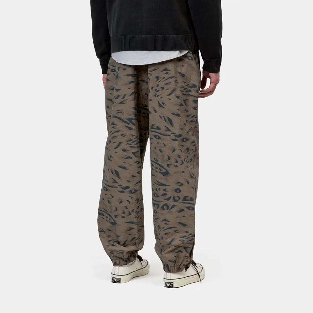 Carhartt WIP Travon Pant in Duck Feather Print Cypress / Black – Rueckansicht am Model der wasserabweisenden Hose mit Entenfeder-Muster und Stickereien.