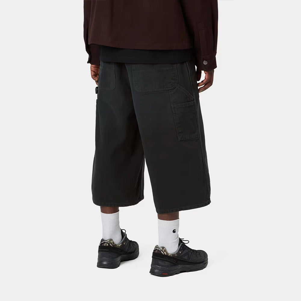 Carhartt WIP OG Single Knee Long Short in Black – Rueckansicht am Model der schwarzen Canvas-Workwear-Shorts mit Tool-Taschen und Hammerlasche.