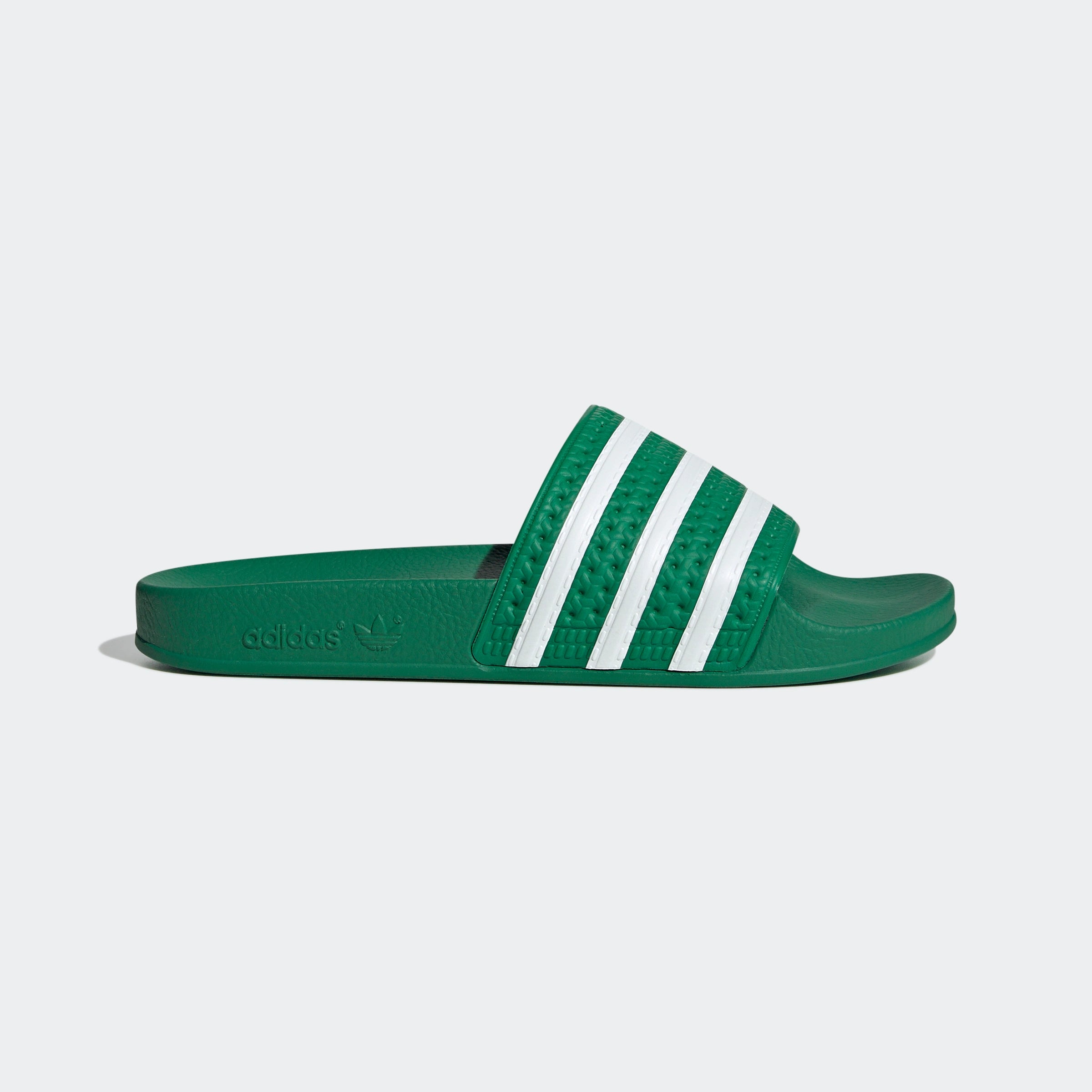 "Grüne Adidas Adilette für Damen mit weißen Details. Klassische Badesandale mit breitem Riemen und weißem Adidas Logo. Bequemes, leichtes Material."