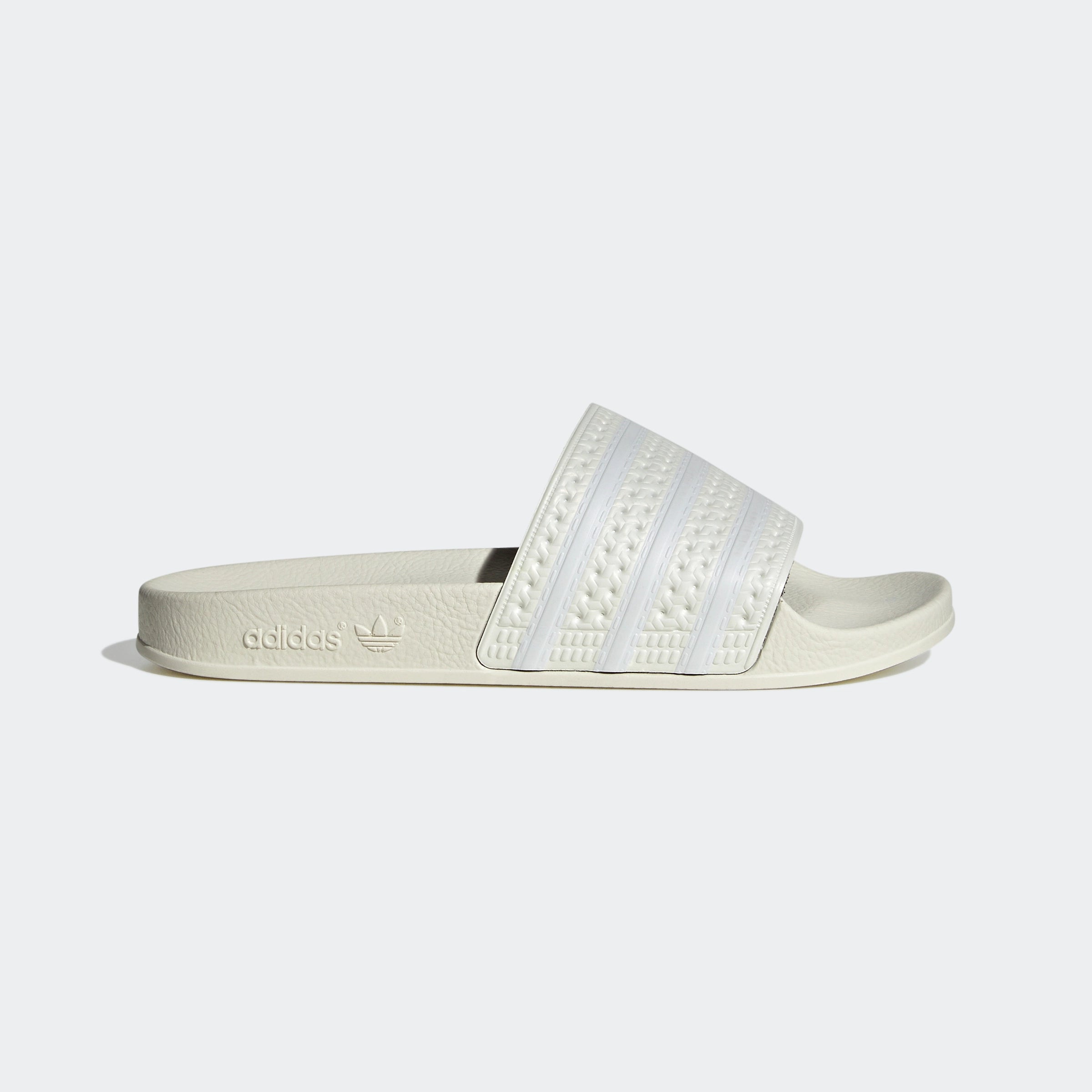 "Off-weiße Adidas Adilette für Damen. Klassische Badesandale mit breitem Riemen und Adidas Logo in derselben Farbe. Bequemes, leichtes Material."