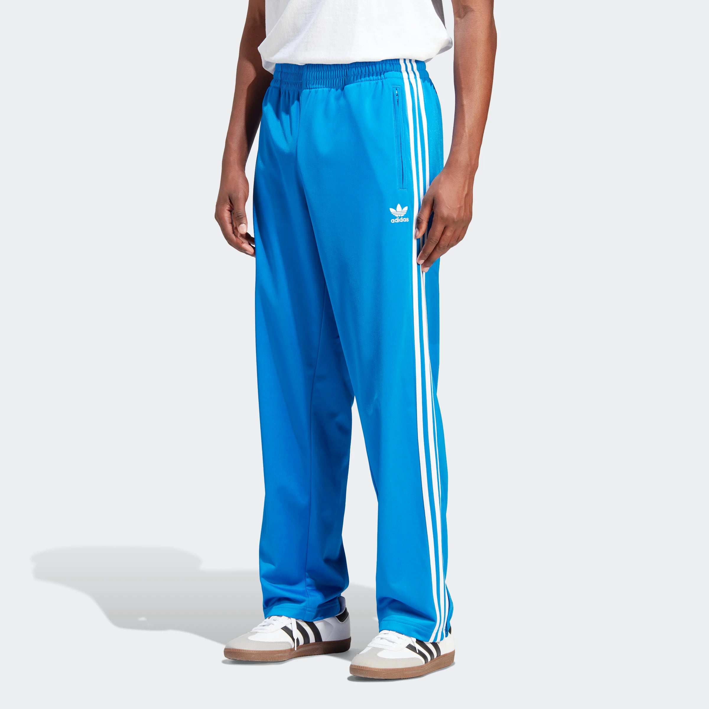 “Die Adidas Originals Classics Firebird Track Pants in Blue Bird/White IJ7056 hat einen elastischen Bund, weiße Seitenstreifen und ein kleines Logo auf der linken Seite. Diese Trainingshose ist ein Muss für jede Sportbekleidungskollektion.“