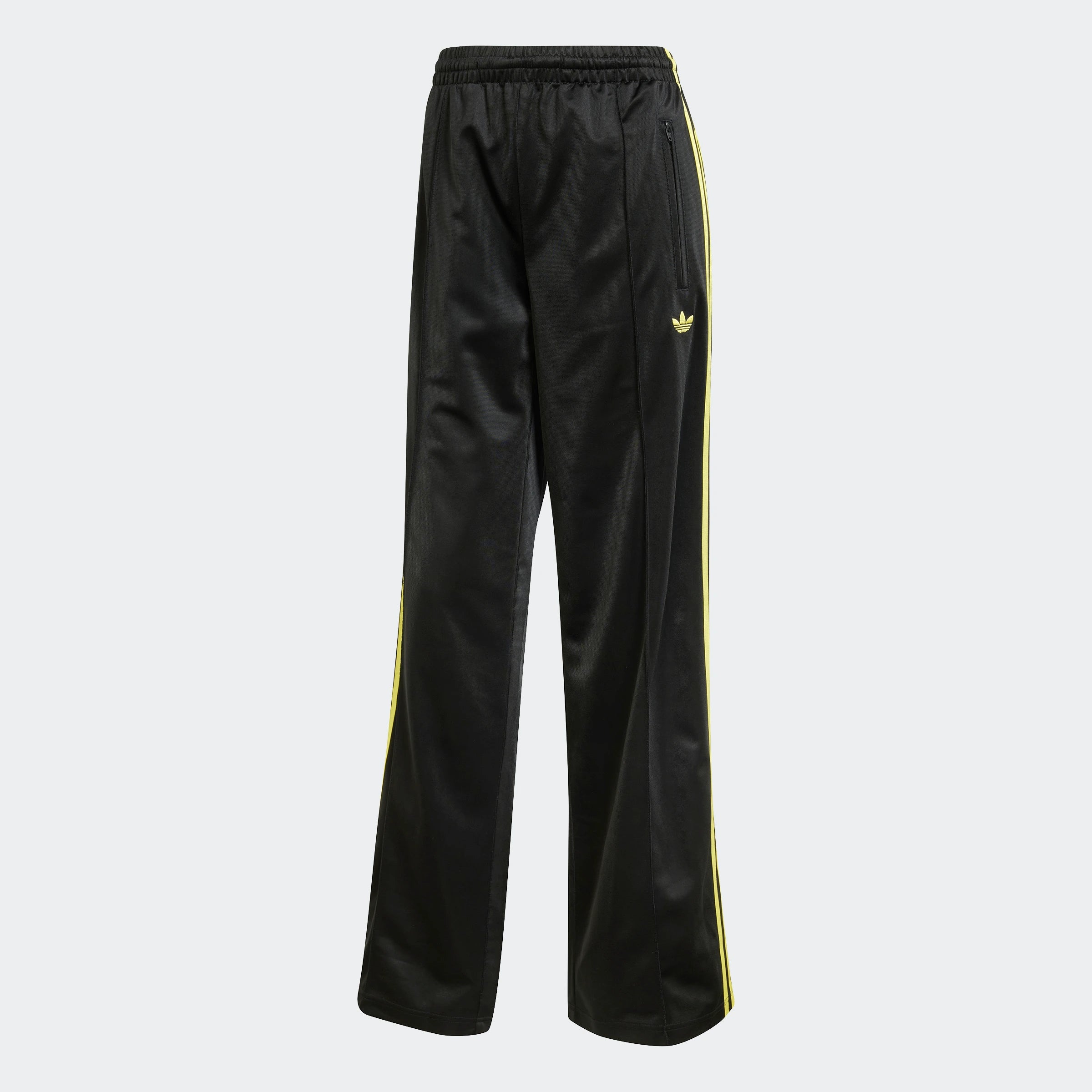 "Schwarze Adidas Firebird Trainingshose für Damen mit hellgelben Seitenstreifen. Lockerer Schnitt, glänzendes Trikotmaterial, seitliche Reißverschlusstaschen, kleines Logo."