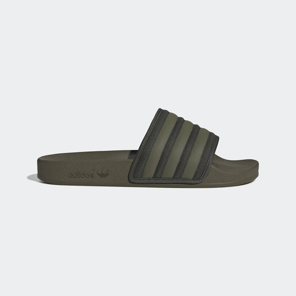 "Slipper von Adidas Adilette in Olivgrün mit einem breiten Riemen mit den drei weißen Streifen und einem vorgeformten Fußbett.“