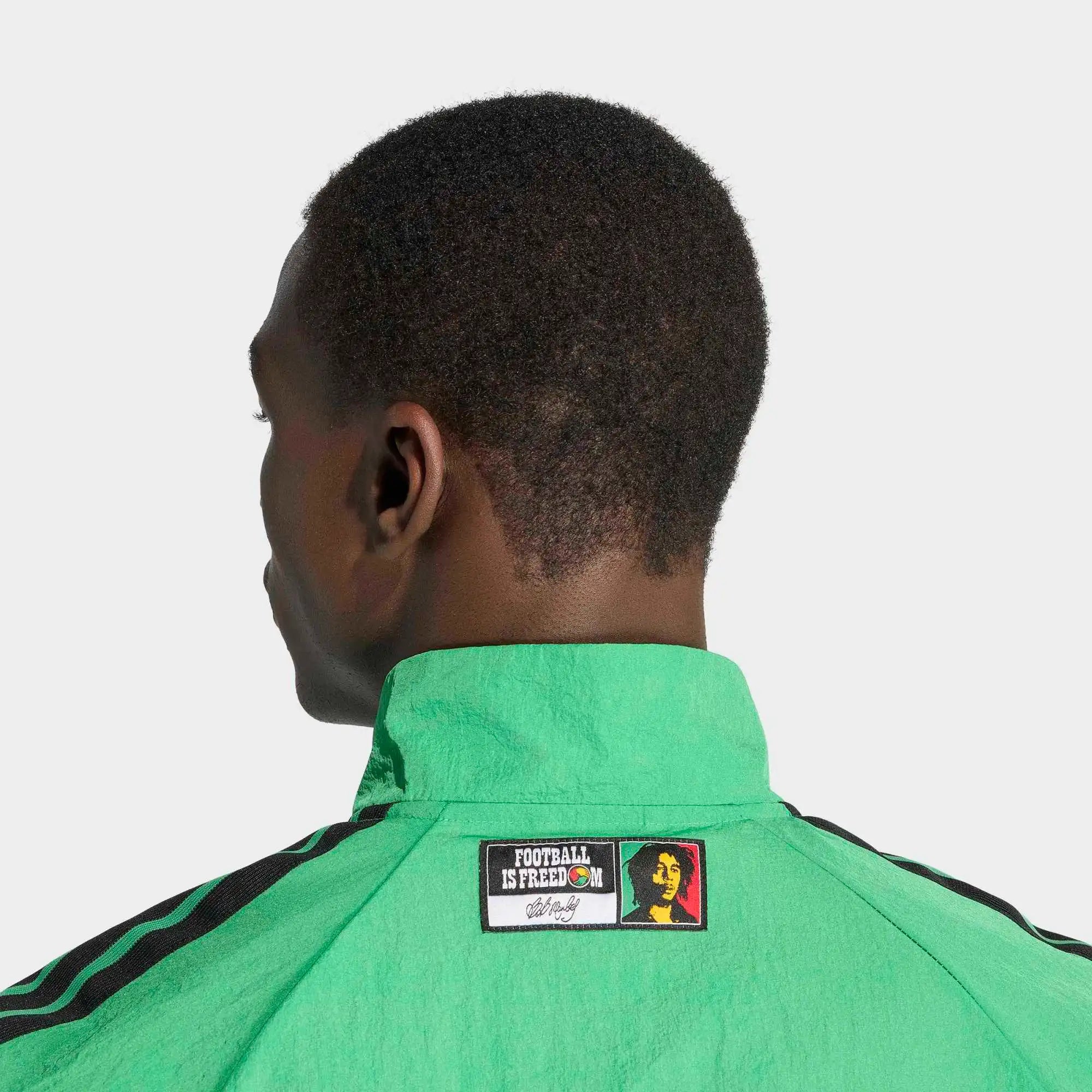 “Adidas Originals Jamaica Home Anthem Jacket in Vivid Green mit gelb-schwarzen Details und dem Logo des jamaikanischen Fußballverbandes bei Stickabush Berlin.“