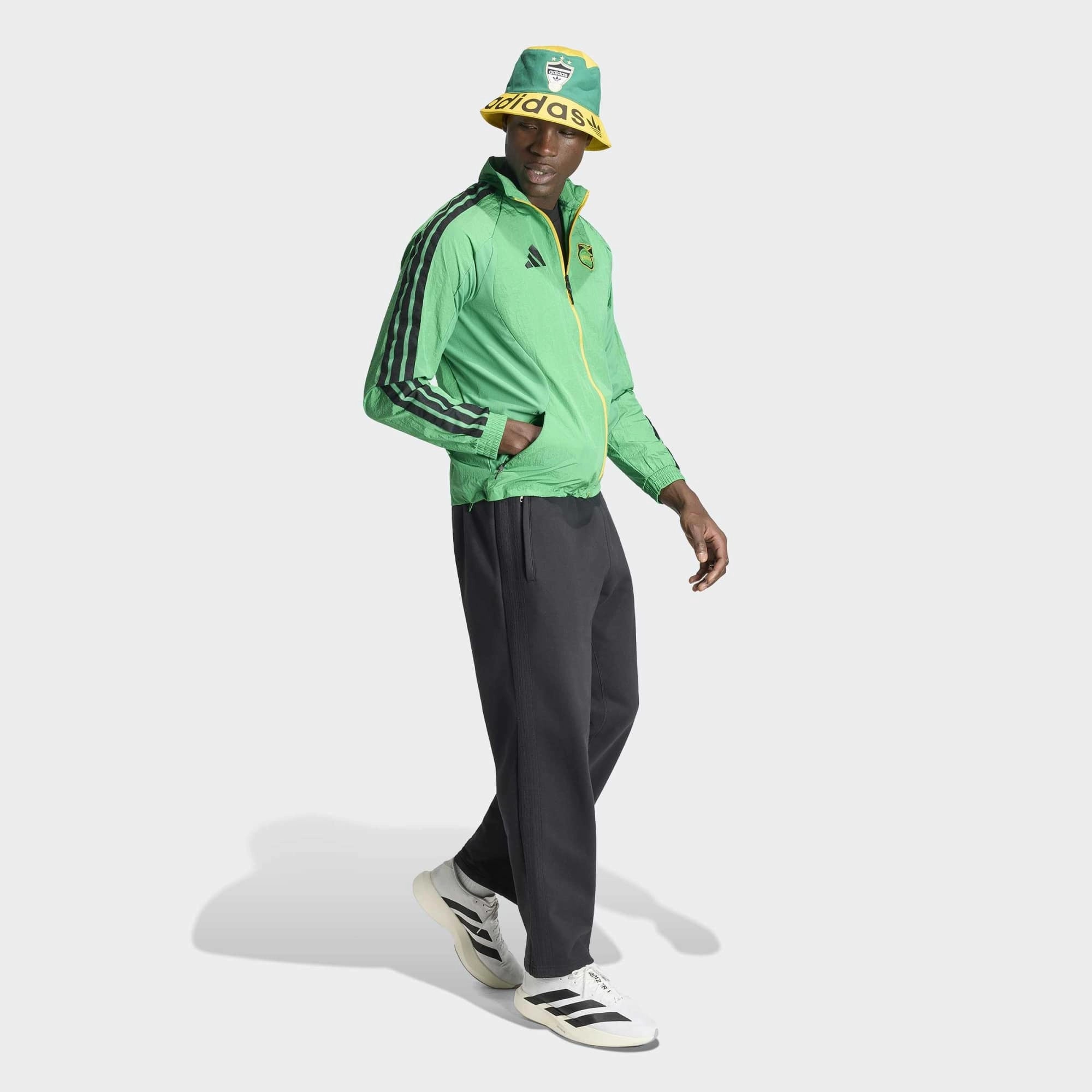 “Adidas Originals Jamaica Home Anthem Jacket in Vivid Green mit gelb-schwarzen Details und dem Logo des jamaikanischen Fußballverbandes bei Stickabush Berlin.“
