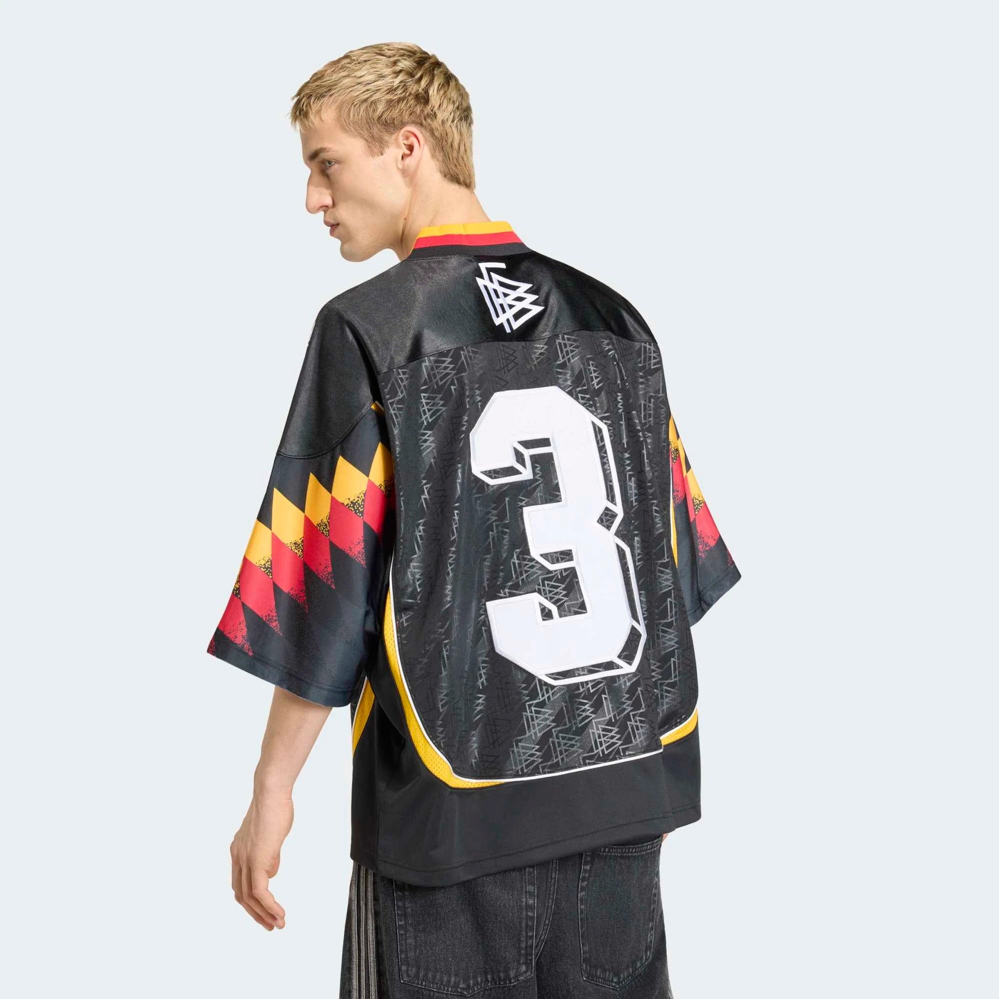 “Hinteransicht Model Outfit des adidas Originals Bringback Remixed DFB Trikots KD5980 in Schwarz mit der großen weißen Nummer 3 und kleinen Nummern an den Schultern bei Stickabush.“