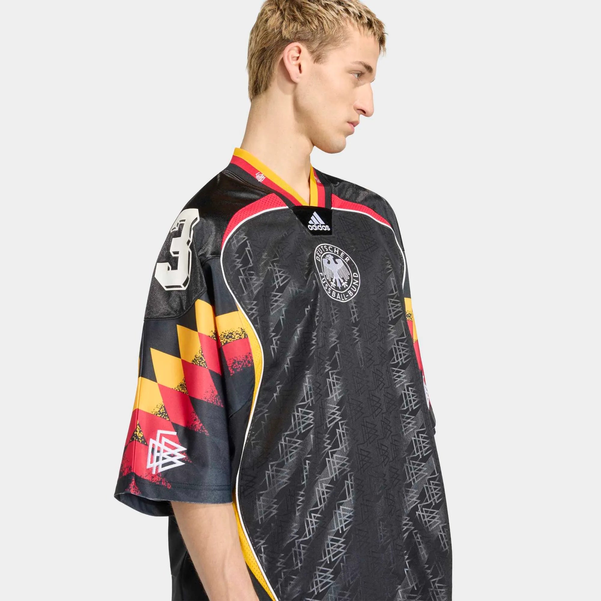 “Seitenansicht Model Outfit des adidas Originals Bringback Remixed DFB Trikots KD5980 in Schwarz mit der großen weißen Nummer 3 und kleinen Nummern an den Schultern bei Stickabush.“