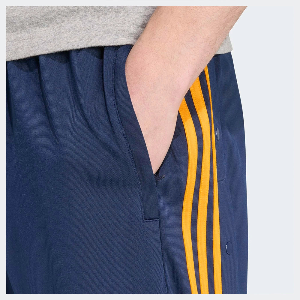 “Adidas Adibreak Track Pants in Blau/Orange, 100% recyceltes Trikot-Material, mit orangefarbenen 3-Streifen und seitlichen Druckknöpfen.“