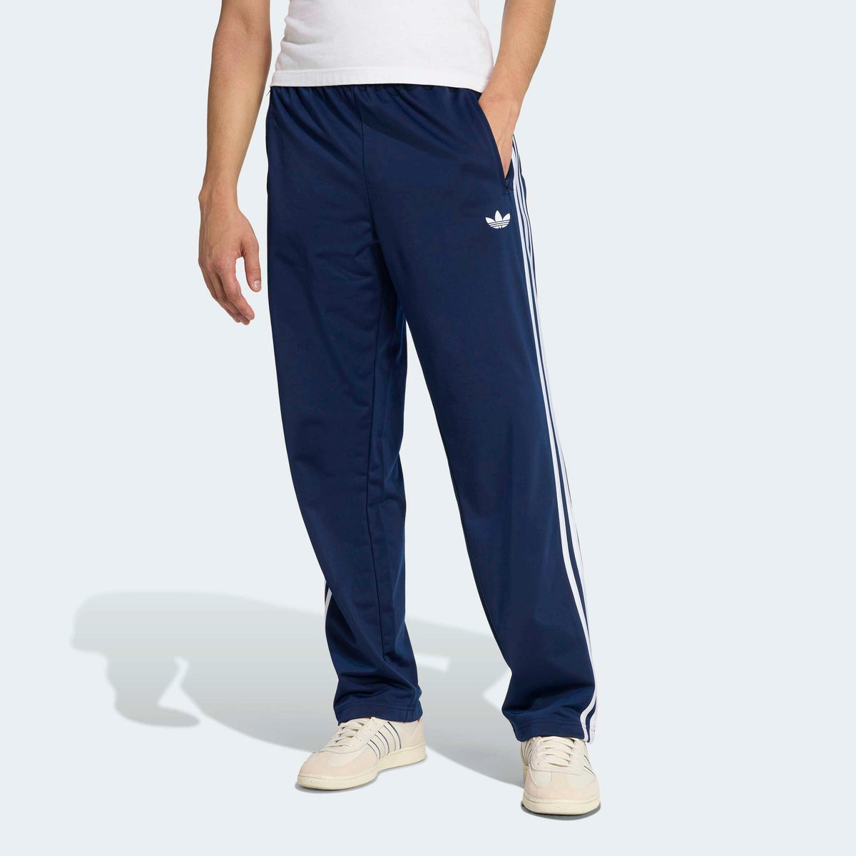 adidas Originals Firebird Track Pants in Night Indigo – Vorderansicht am Model der dunkelblauen Trainingshose im Retro-Look mit den ikonischen 3-Stripes.
