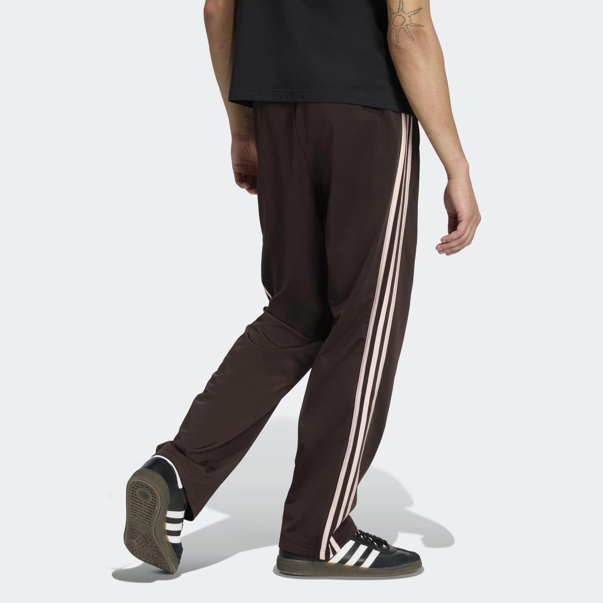 “Rückansicht Model Outfit der Adidas Originals Firebird Track Pants in Aurora Coffee (Braun) mit weißen Streifen – Klassische Retro-Hose bei Stickabush Berlin.“