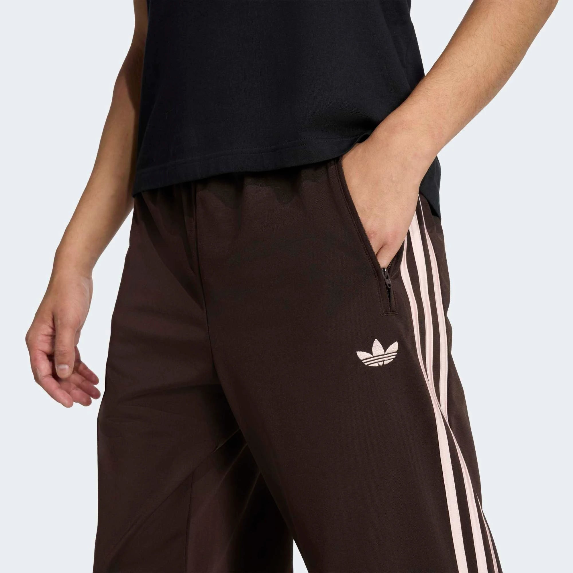 “Vorderansicht Model Detail der Adidas Originals Firebird Track Pants in Aurora Coffee (Braun) mit weißen Streifen – Klassische Retro-Hose bei Stickabush Berlin.“