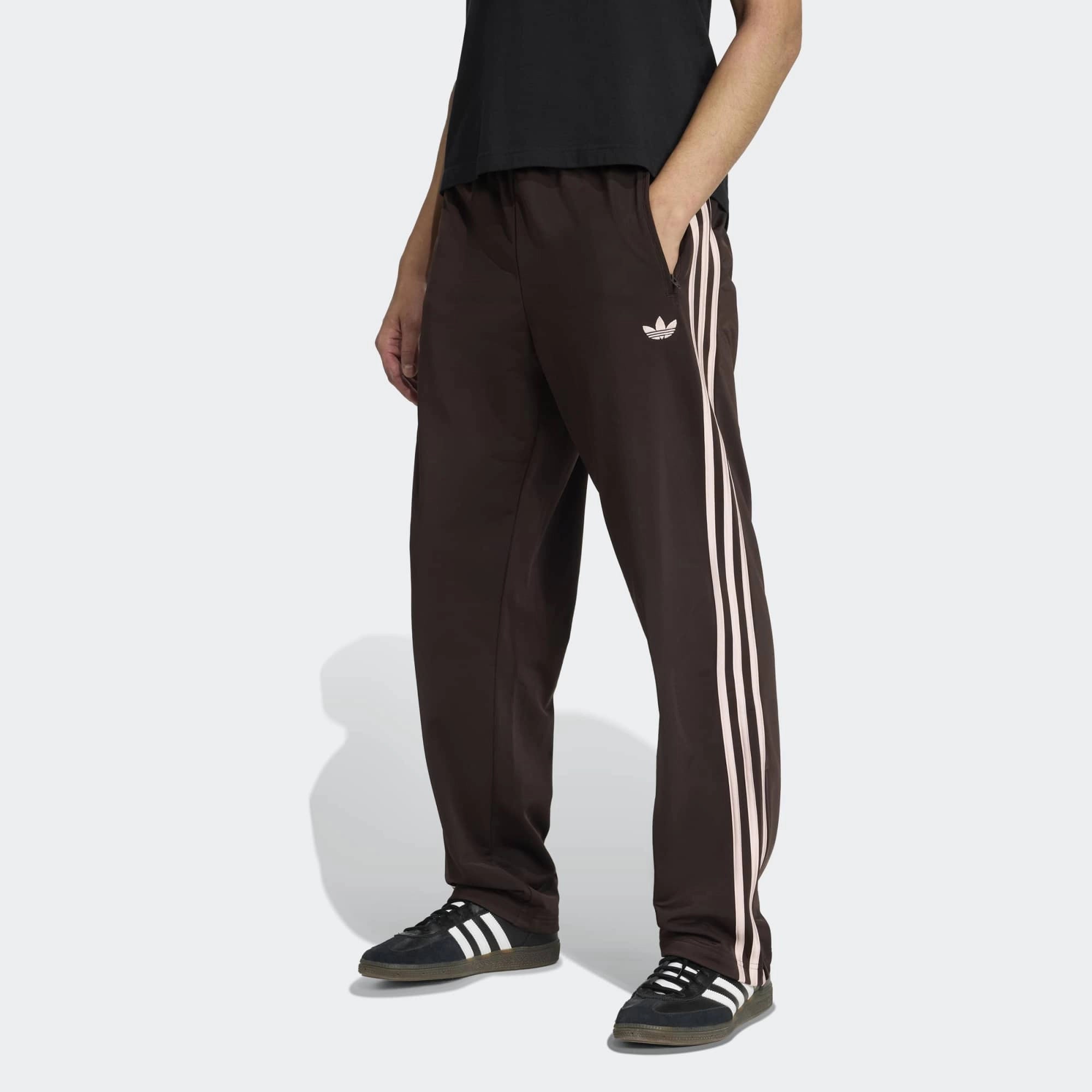 “Vorderansicht Model Outfit der Adidas Originals Firebird Track Pants in Aurora Coffee (Braun) mit weißen Streifen – Klassische Retro-Hose bei Stickabush Berlin.“