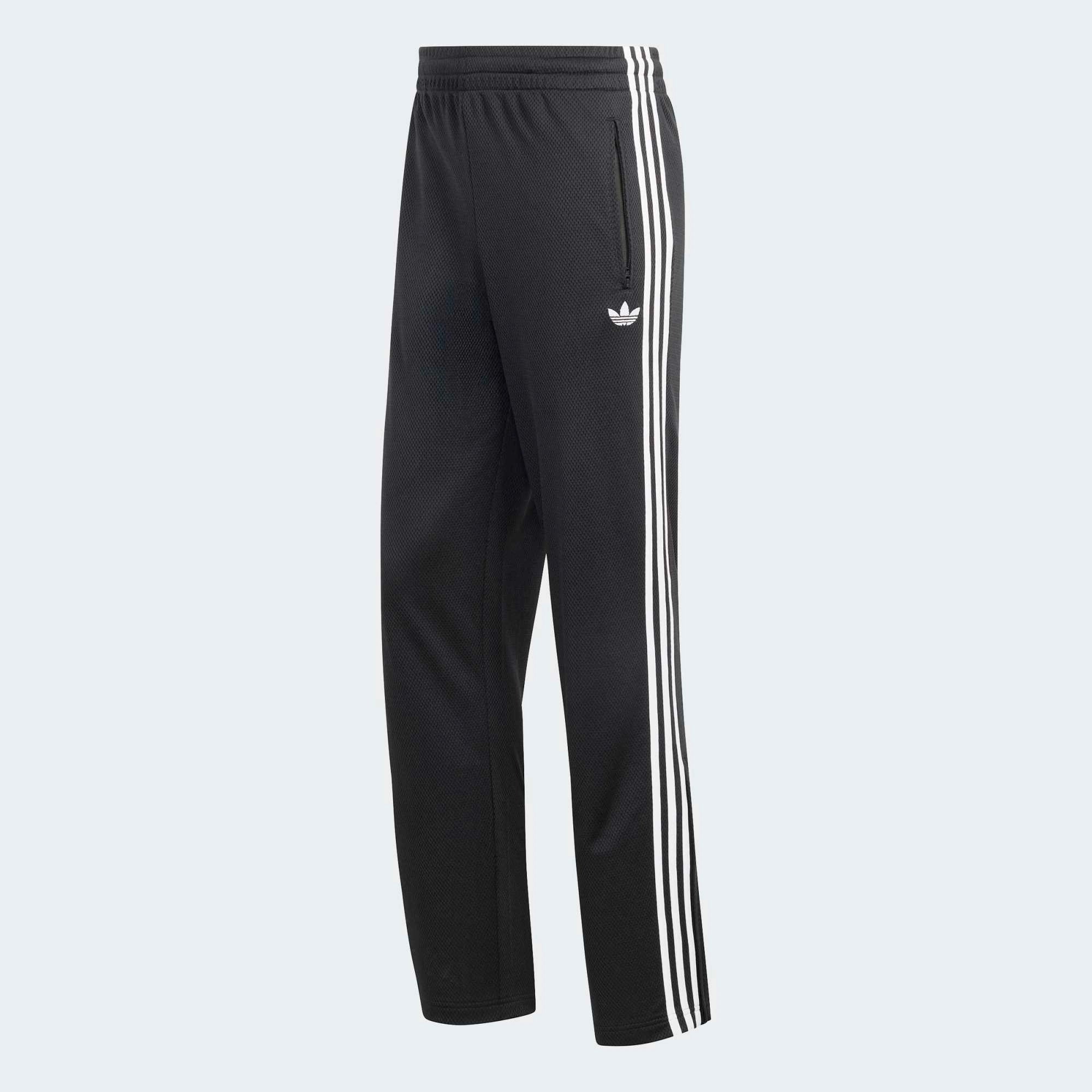 “Adidas Originals Firebird Track Pants Mesh in Schwarz mit weißen Streifen, Frontansicht des Trefoil-Logos und Mesh-Textur bei Stickabush Berlin.“