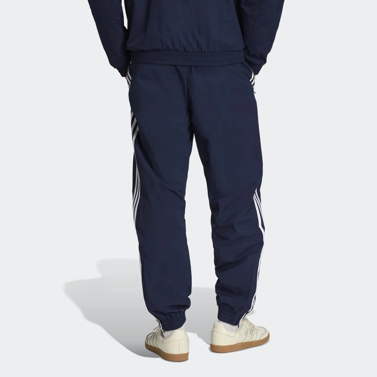 “Die adidas Originals Firebird Woven Trainingshose in Night Indigo (Dunkelblau) mit weißen 3-Streifen und leichtes, strapazierfähiges Webmaterial (Woven) bei Stickabush“.