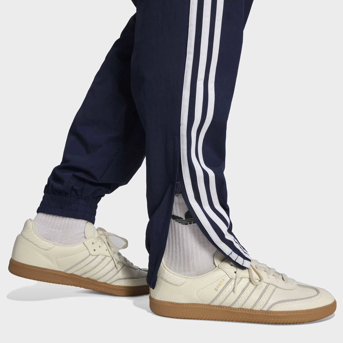 “Die adidas Originals Firebird Woven Trainingshose in Night Indigo (Dunkelblau) mit weißen 3-Streifen und leichtes, strapazierfähiges Webmaterial (Woven) bei Stickabush“.
