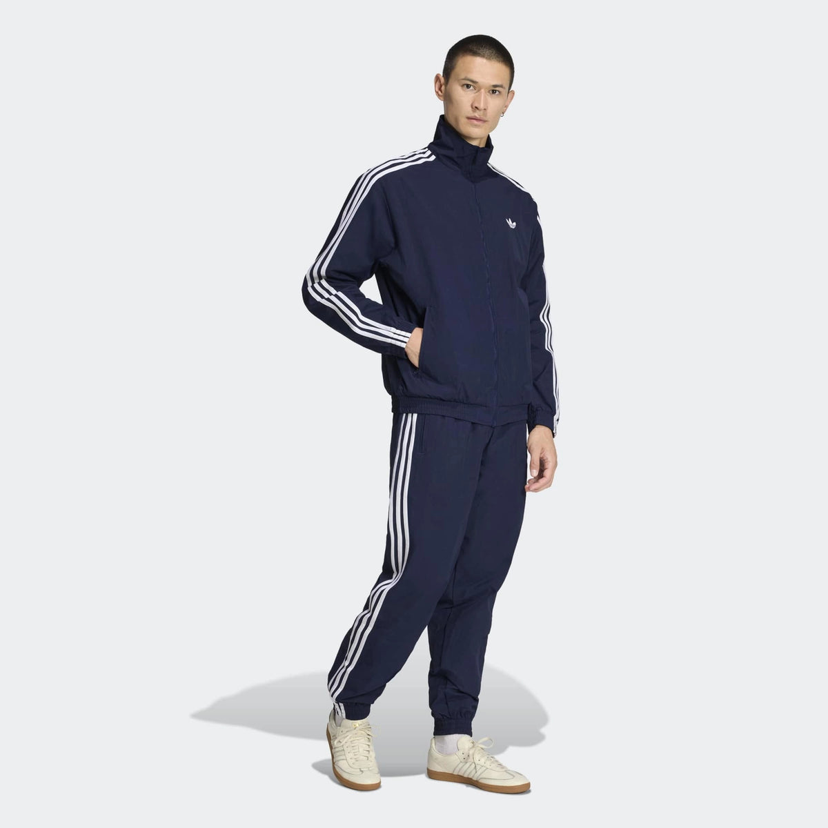 “Die adidas Originals Firebird Woven Trainingshose in Night Indigo (Dunkelblau) mit weißen 3-Streifen und leichtes, strapazierfähiges Webmaterial (Woven) bei Stickabush“.