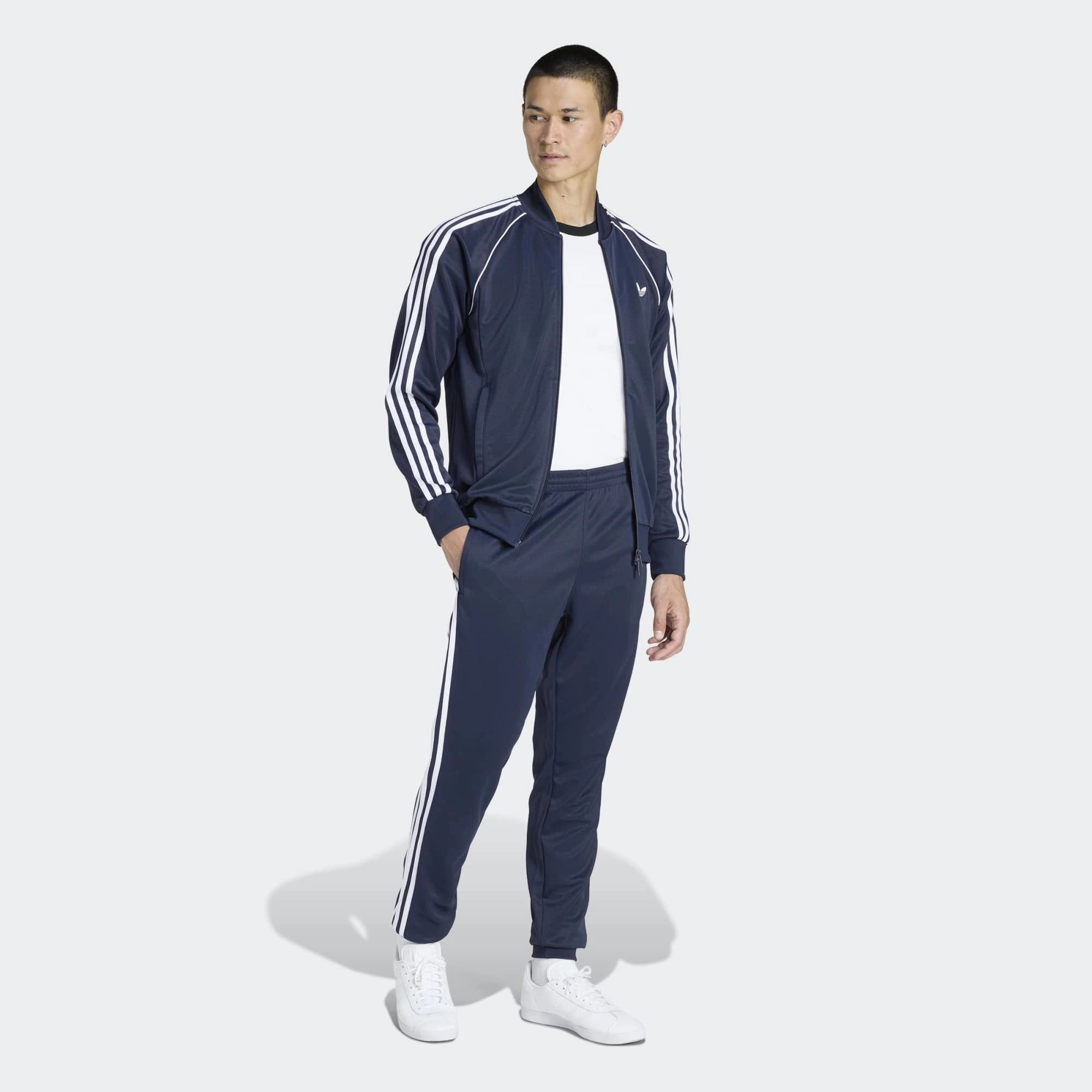 "Dunkelblaue adidas Originals SST Track Pant (Night Indigo) mit weißen 3-Streifen, Trefoil-Stickerei und Reißverschlusstaschen bei Stickabush Berlin."