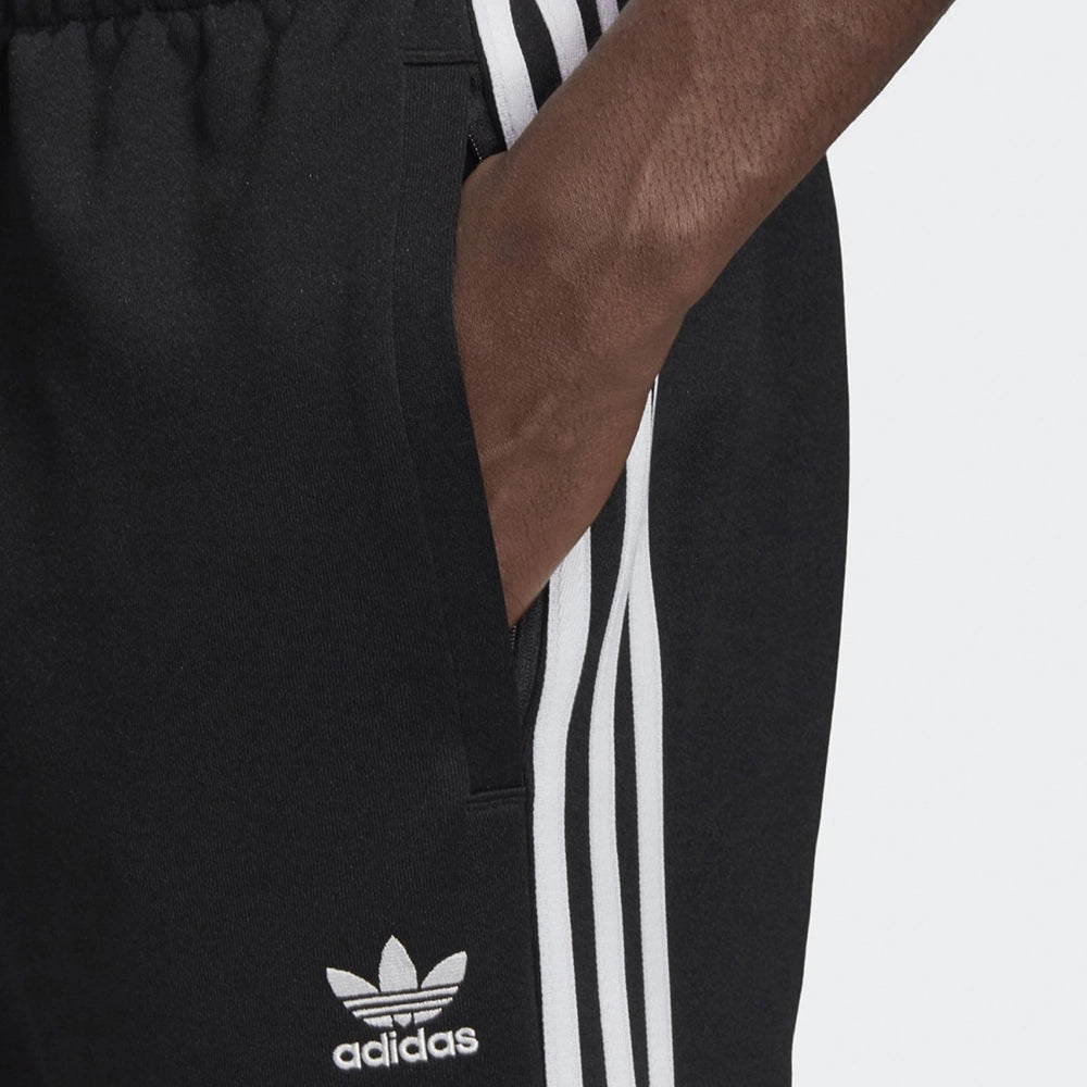"Schwarze adidas Classics SST Trainingshose mit weißen 3-Streifen, Trefoil-Logo und schmal zulaufendem Bein bei Stickabush Berlin."