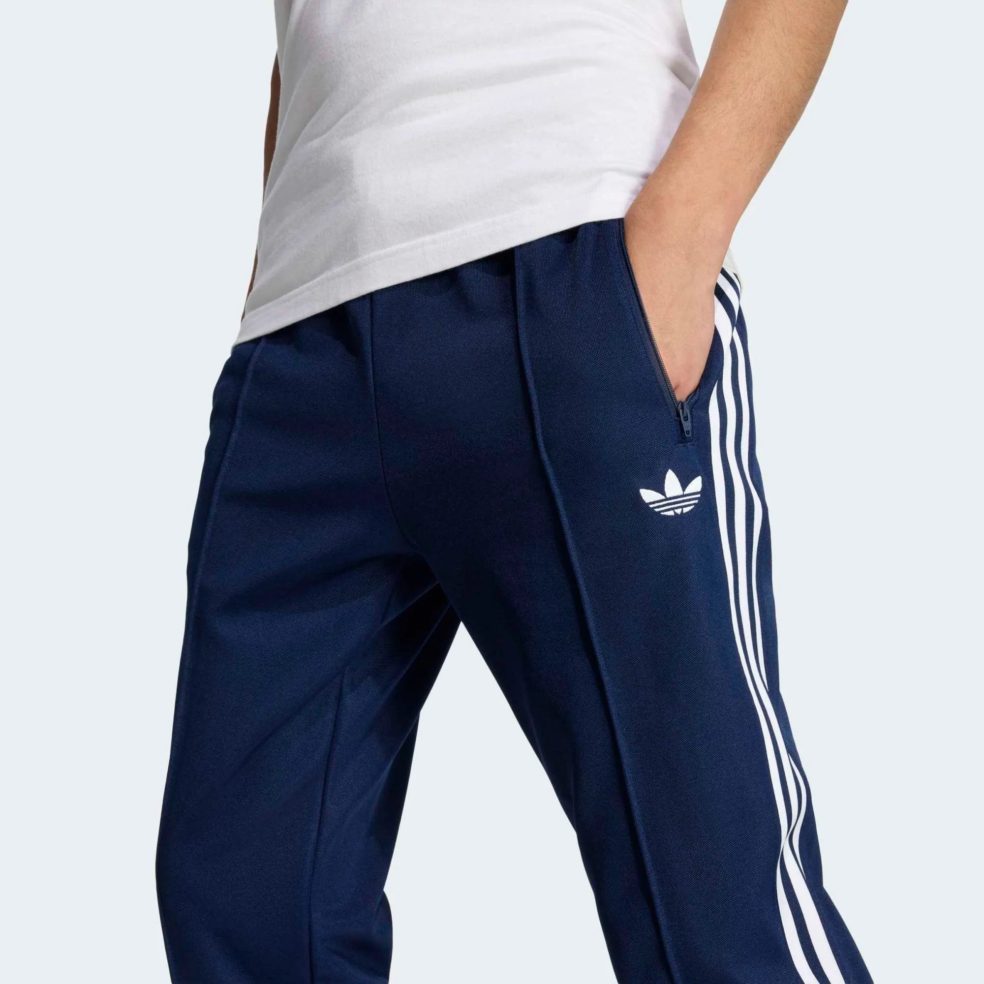 „Dunkelblaue Adidas Originals Beckenbauer Track Pant (Night Indigo) mit weißen 3-Streifen und klassischer Bügelfalte bei Stickabush Berlin.“