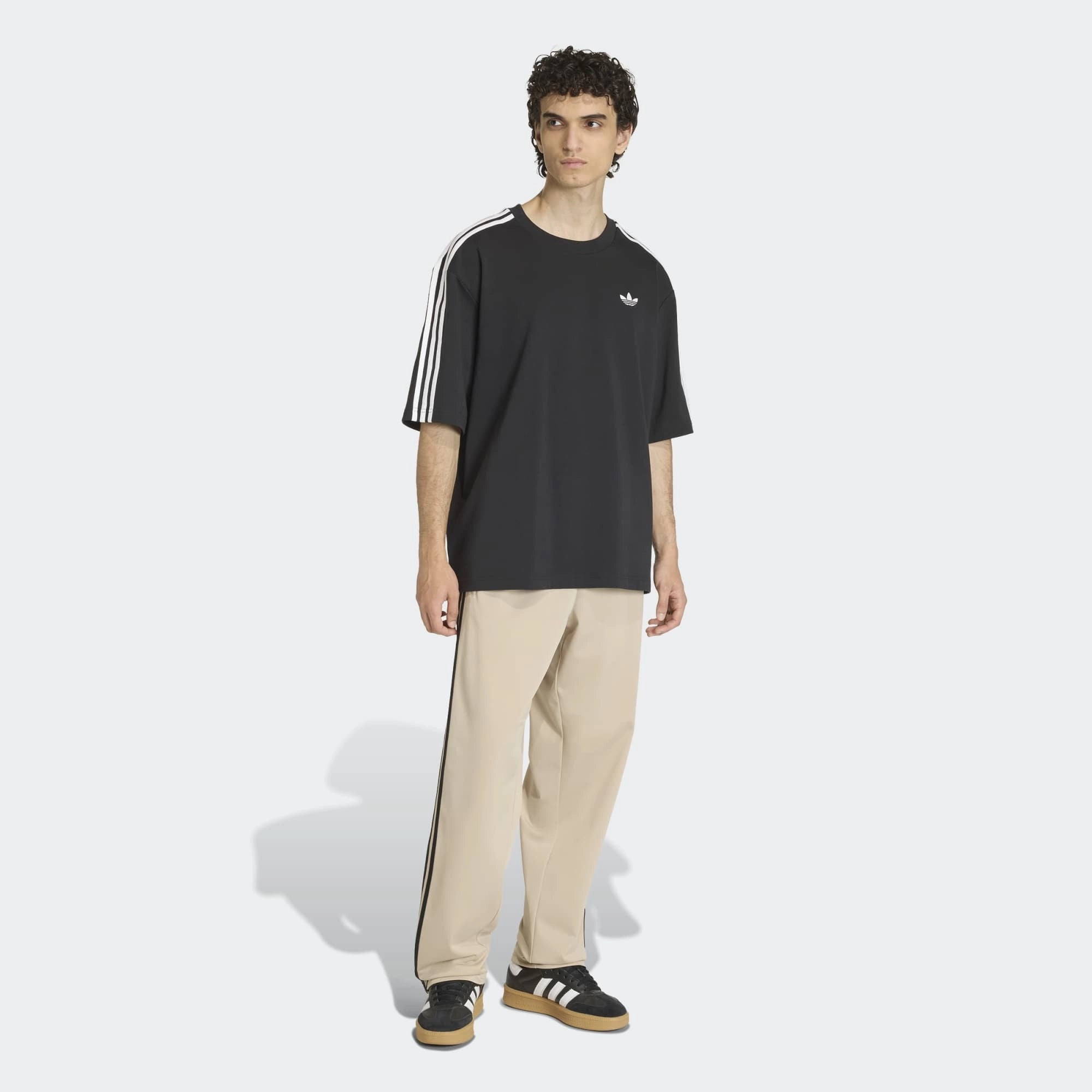 “Adidas Originals Firebird Track Pants in Stone Khaki mit schwarzen Streifen und gesticktem Trefoil-Logo bei Stickabush Berlin.“