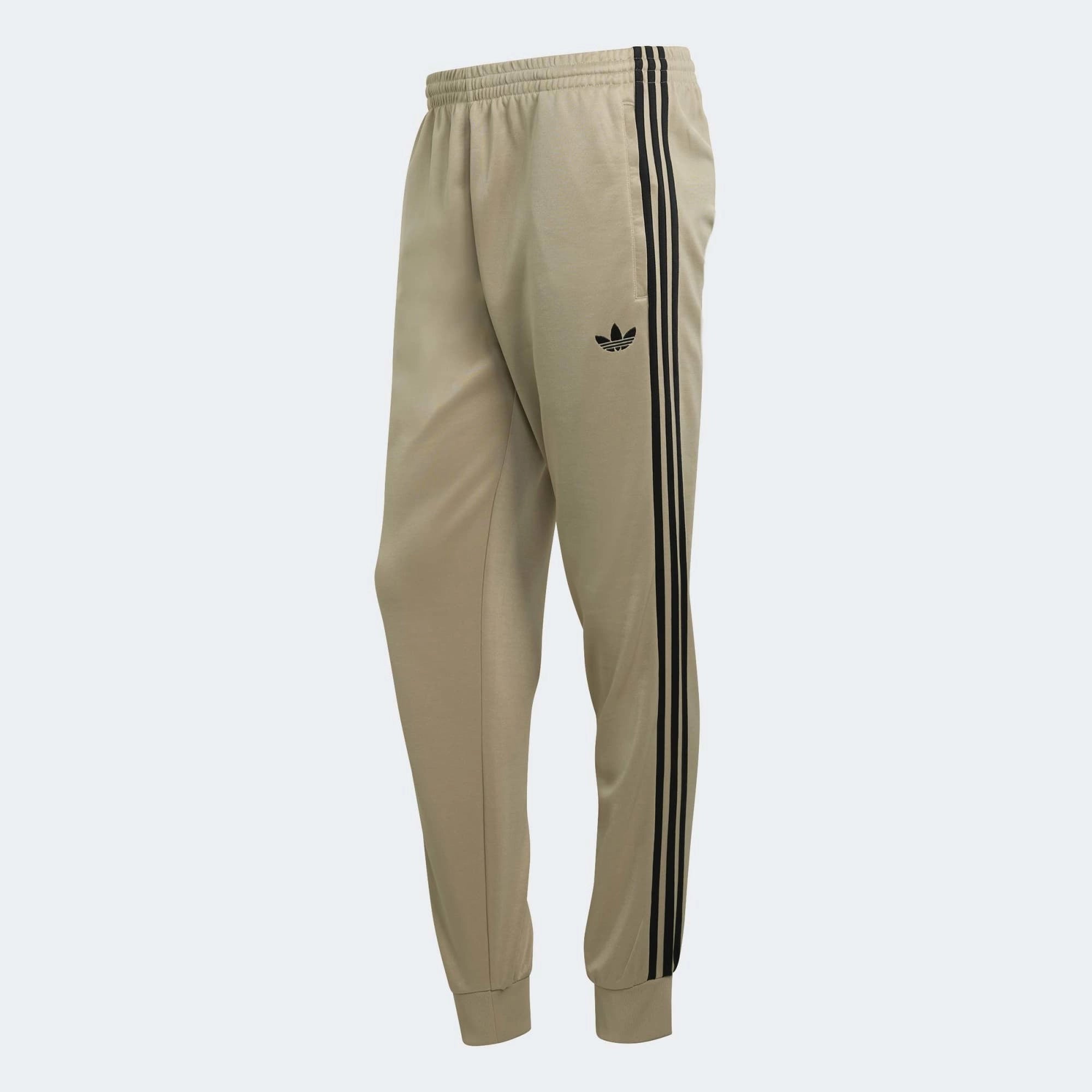 „Khakifarbene adidas Originals Firebird Trainingshose mit schwarzen 3-Streifen, gesticktem Trefoil-Logo und geradem Beinschnitt bei Stickabush Berlin.“