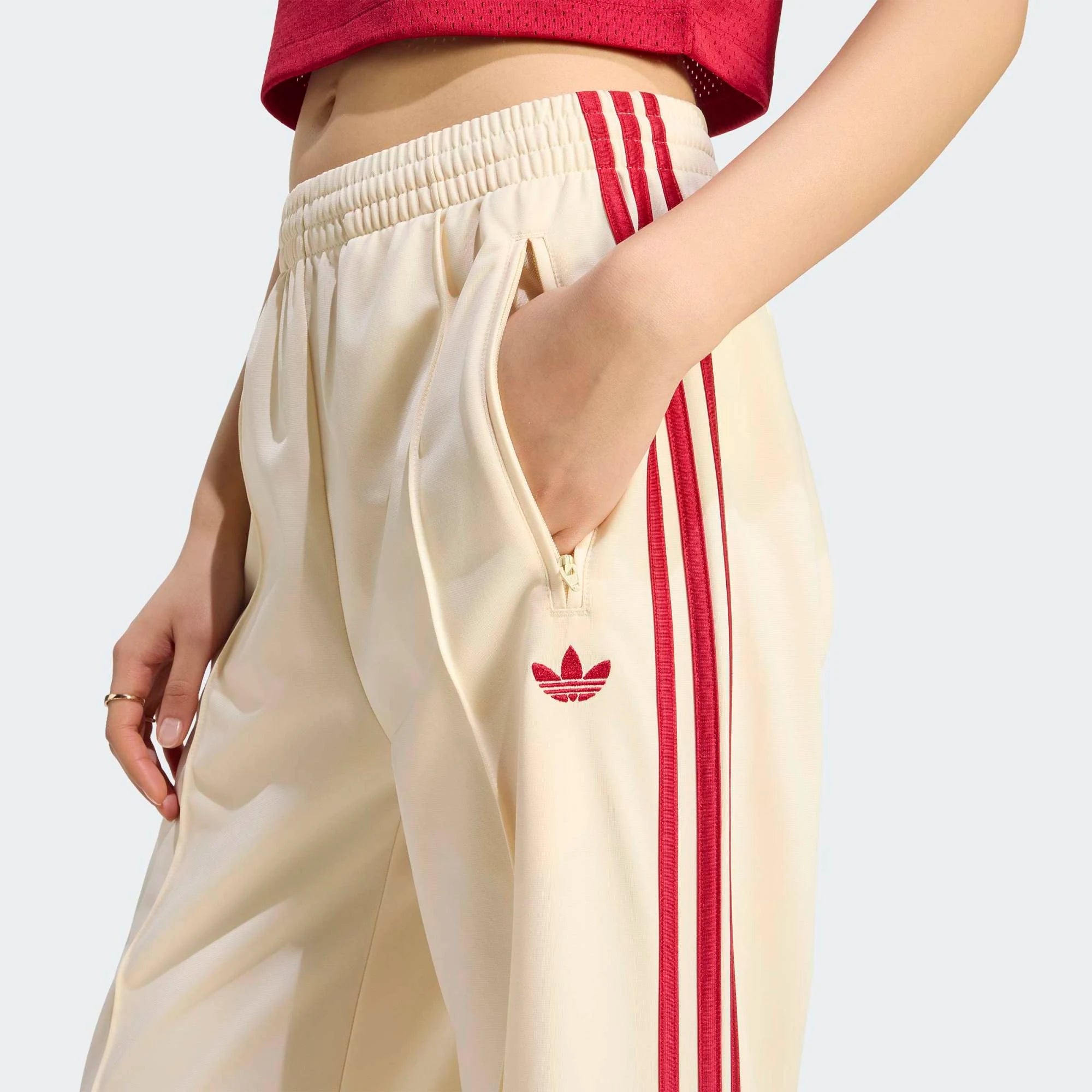 “adidas Originals Firebird Loose Damen Trainingshose in hellem Vanilla-Weiß mit roten drei Streifen und Trefoil-Logo bei Stickabush Berlin.“ 