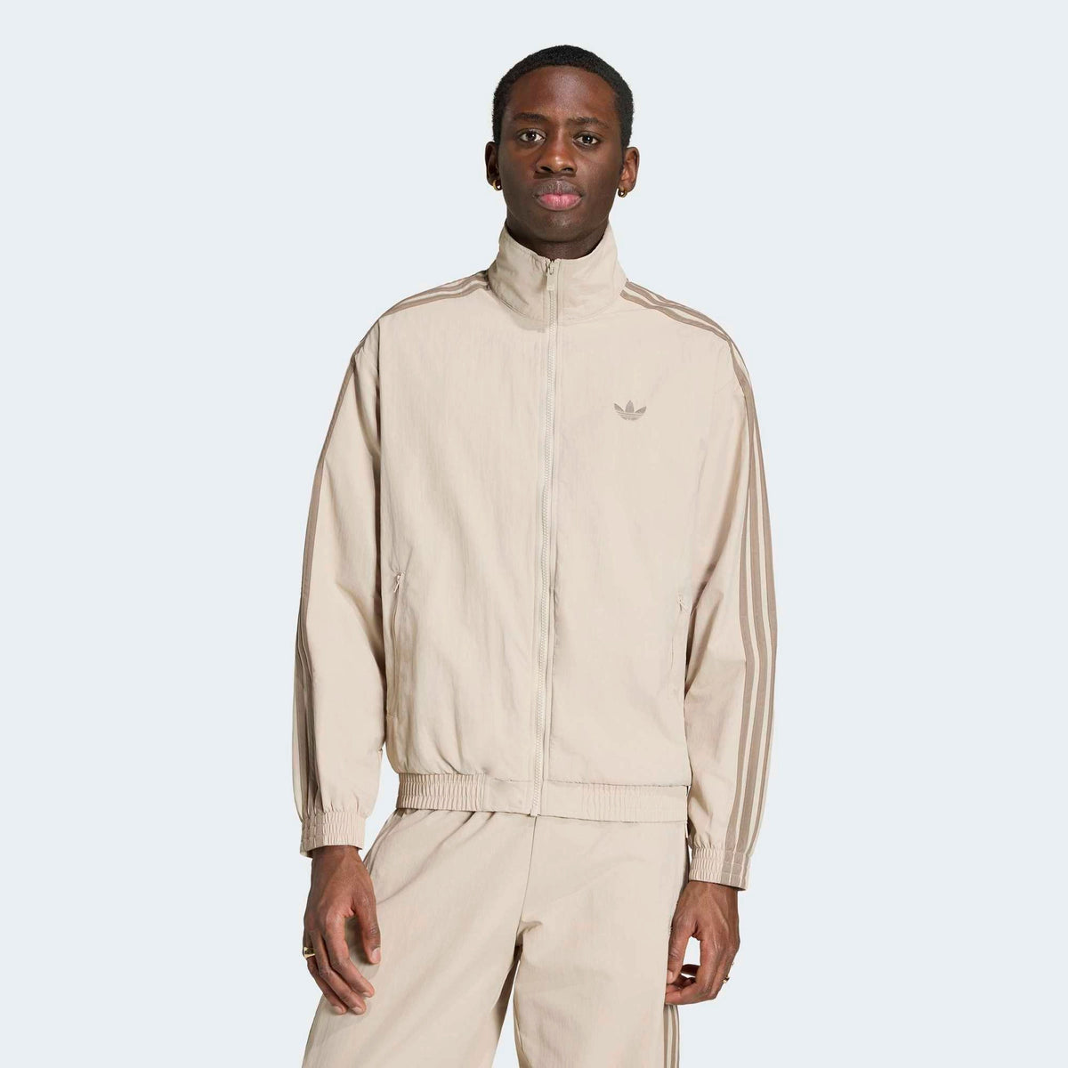 adidas Originals Firebird Woven Track Top in Beige am Model von vorne, hochauflösend präsentiert im STICKABUSH Store Berlin.
