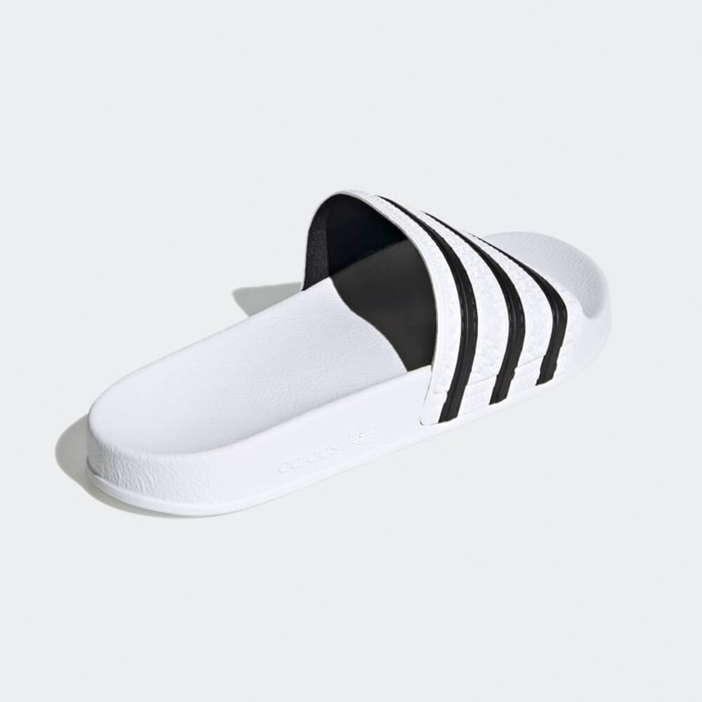 “Außenansicht der Adidas Originals Adilette in White / Black – Klassische Badeschlappen mit weißen 3-Streifen auf schwarzem Riemen und vorgeformtem Fußbett bei Stickabush Berlin.“