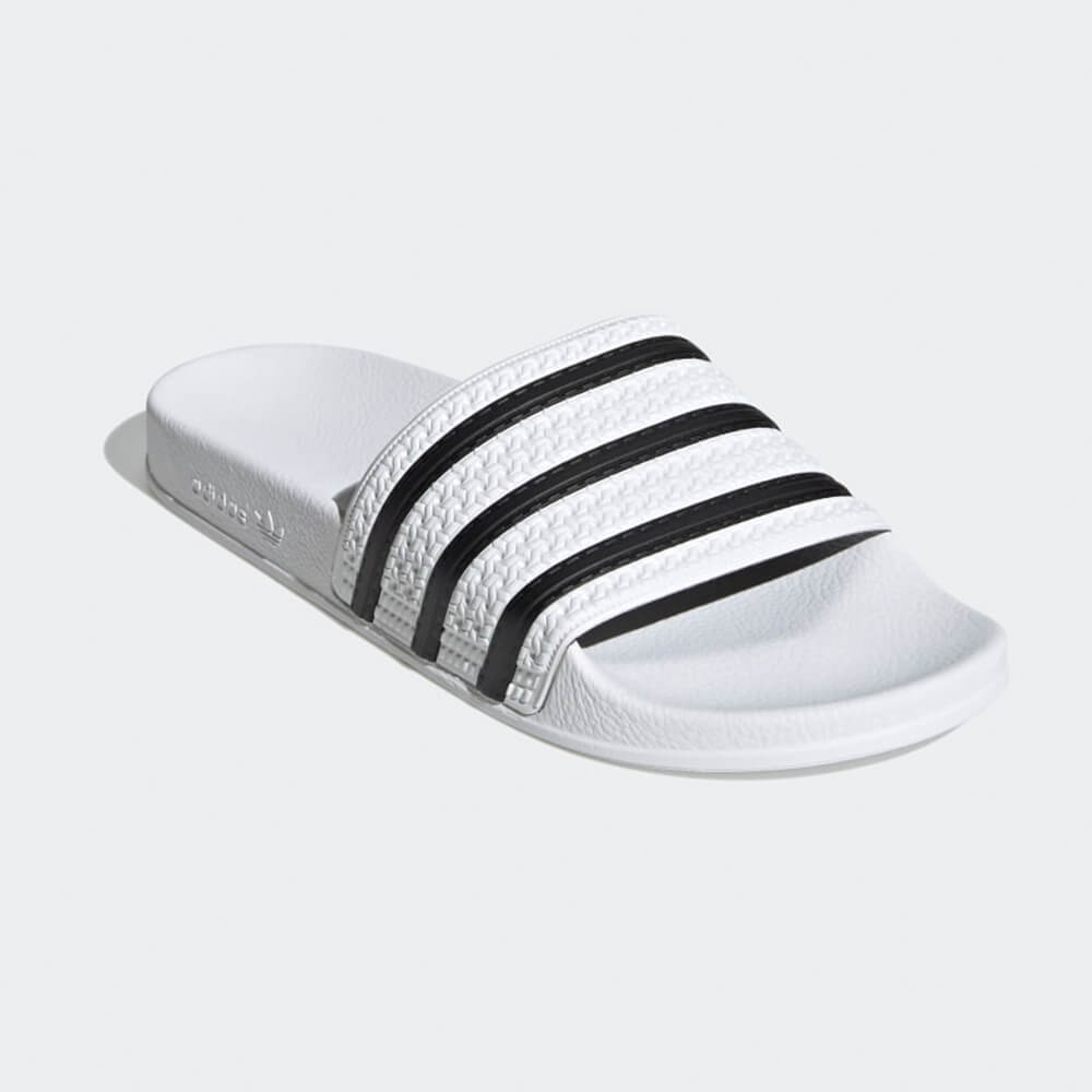 “Frontansicht der Adidas Originals Adilette in White / Black – Klassische Badeschlappen mit weißen 3-Streifen auf schwarzem Riemen und vorgeformtem Fußbett bei Stickabush Berlin.“