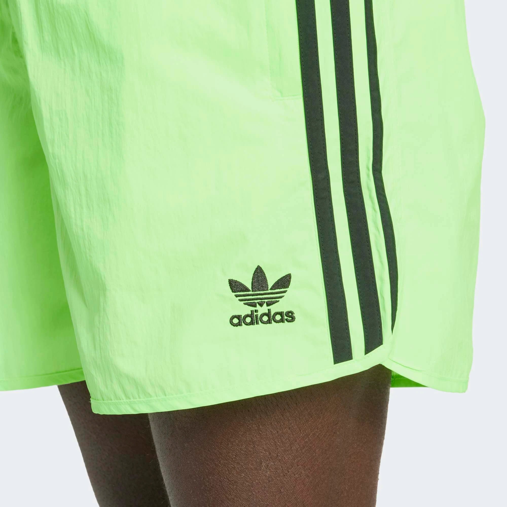 “Adidas Classics Sprinter Shorts in Signal Green – Kurze Retro-Sporthose mit schwarzen 3-Streifen, Trefoil-Logo und Reißverschlusstaschen bei Stickabush Berlin.“