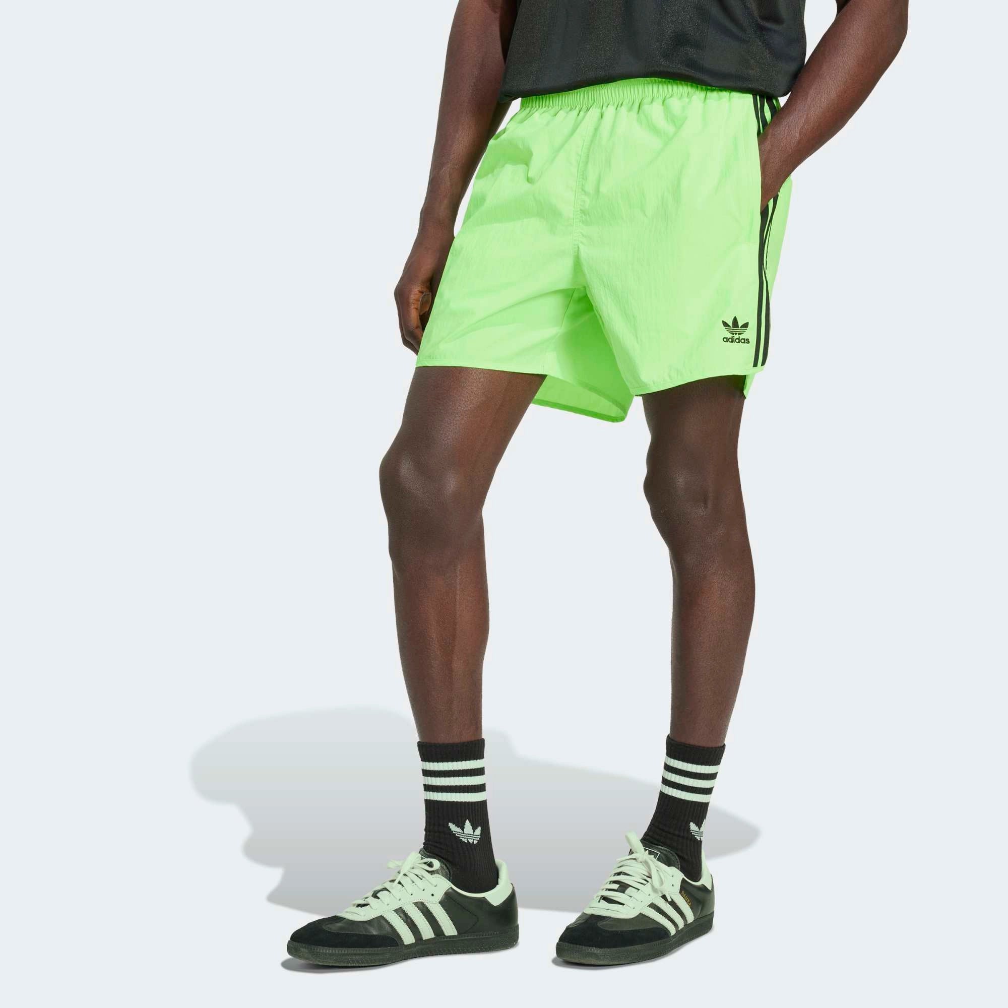 “Adidas Classics Sprinter Shorts in Signal Green – Kurze Retro-Sporthose mit schwarzen 3-Streifen, Trefoil-Logo und Reißverschlusstaschen bei Stickabush Berlin.“