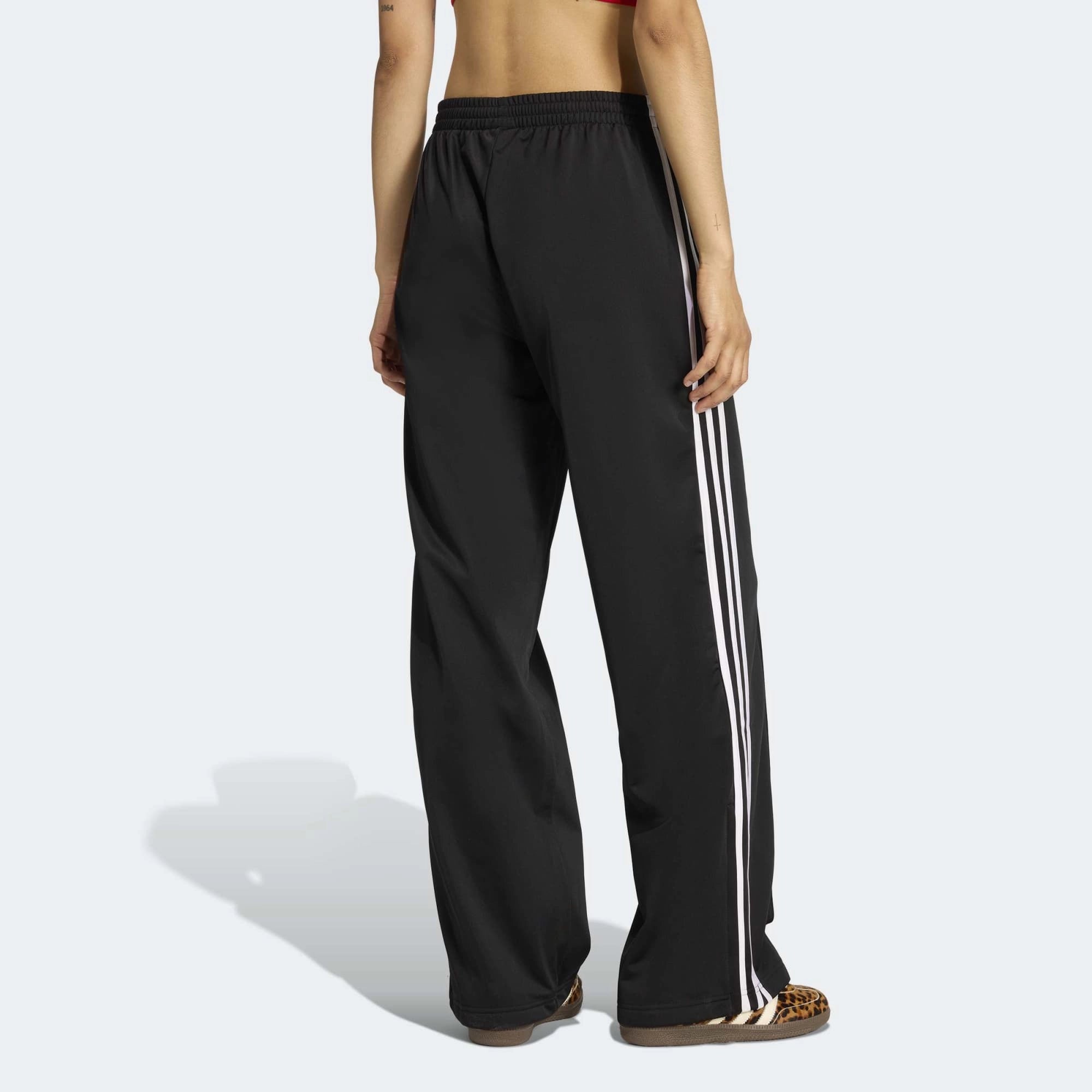 „Schwarze adidas Originals Firebird Loose Track Pants für Damen mit weißen 3-Streifen (Style-ID: KD7976) – weit geschnittene Streetwear-Trainingshose aus Trikot-Stoff bei Stickabush Berlin.“