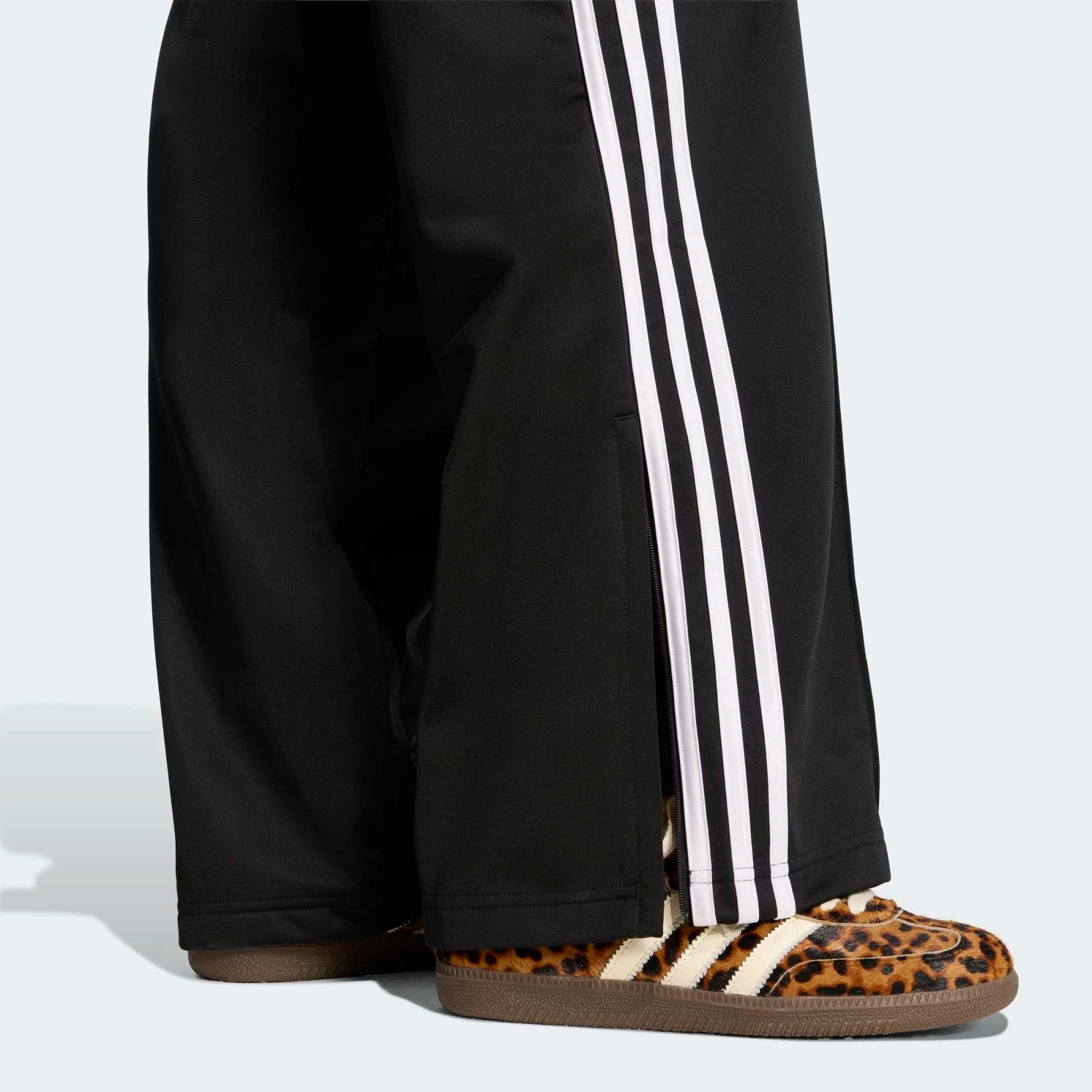 „Schwarze adidas Originals Firebird Loose Track Pants für Damen mit weißen 3-Streifen (Style-ID: KD7976) – weit geschnittene Streetwear-Trainingshose aus Trikot-Stoff bei Stickabush Berlin.“